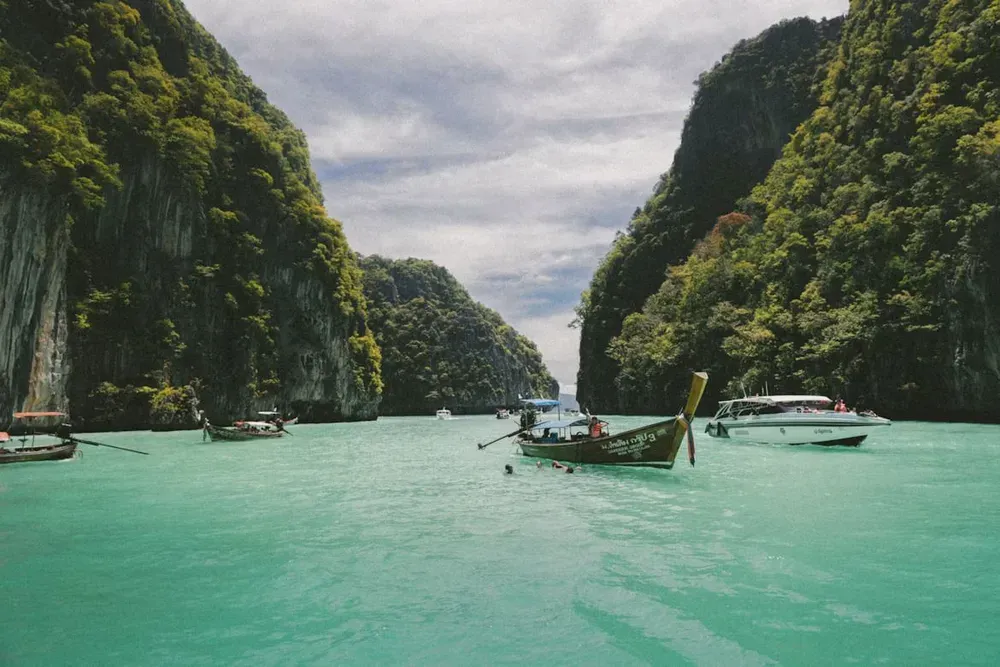 A Thai longboat sailing between large limestone karsts