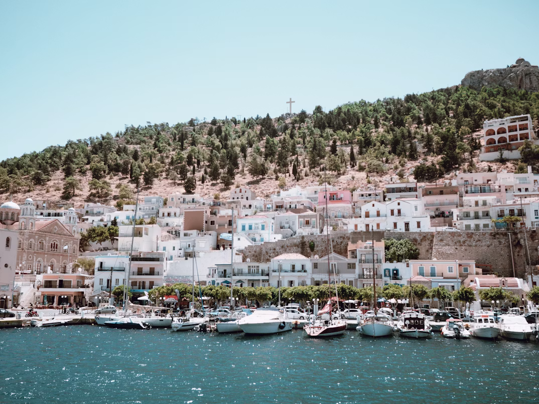 A harbour lined with docked boats and a steep hill in the backdrop