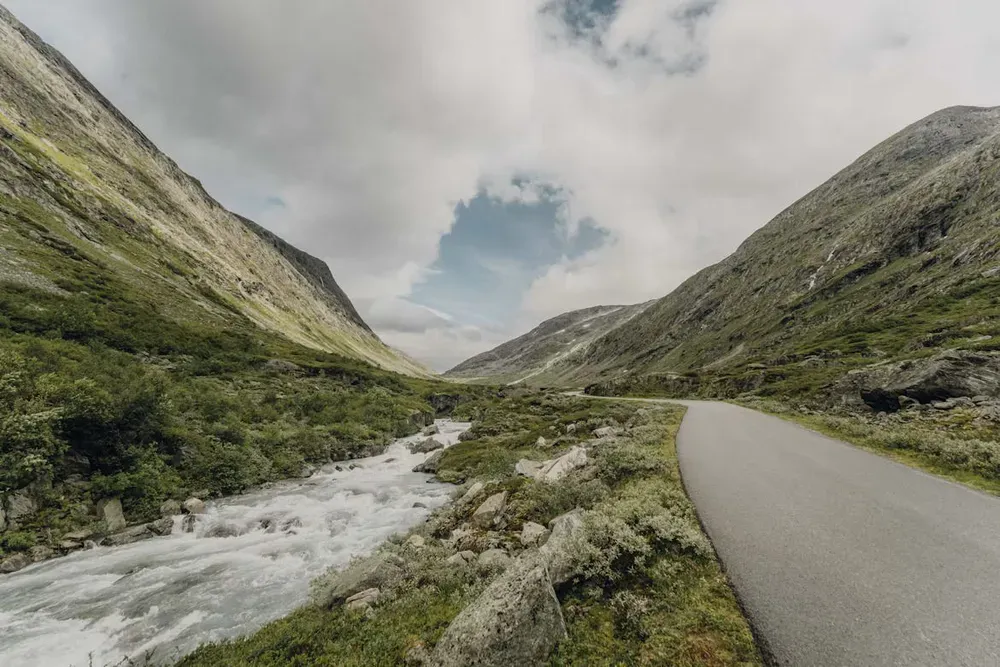 A long empty road beside a gushing river