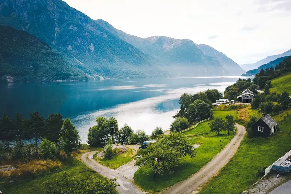 An aerial view of a fjord with leafy mountains rising in the background