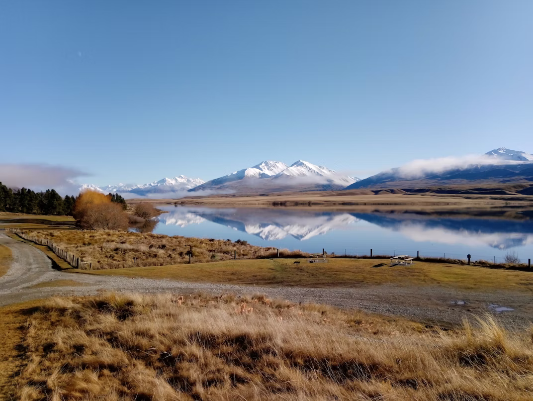 Schneebedeckte Berge spiegeln sich im klaren Wasser des Clearwater-See im Hakatere Conservation Park in Neuseeland.