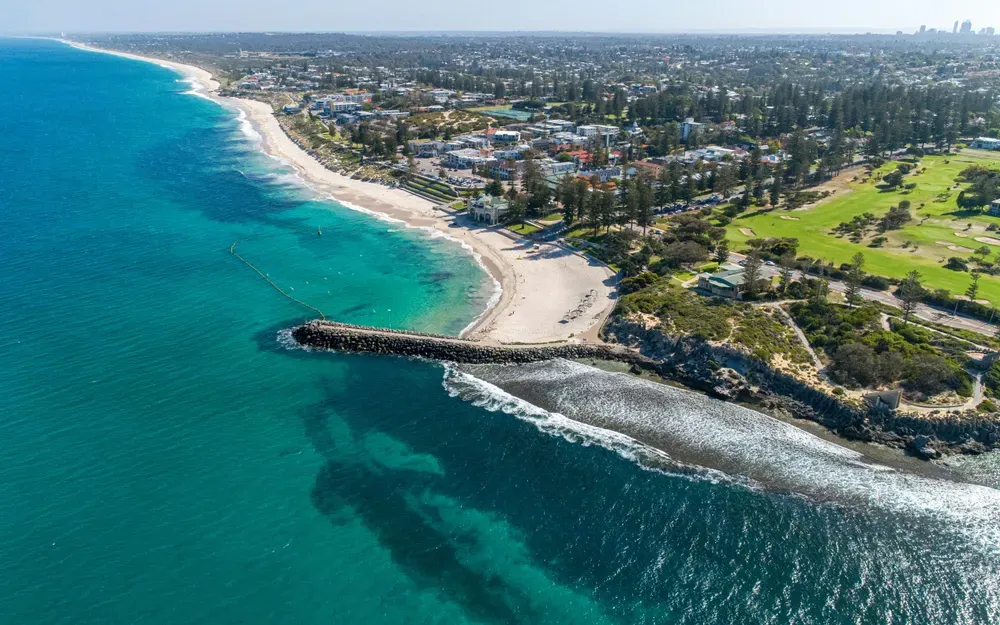 Eine Luftaufnahme des Cottesloe Beach in Perth, Australien, mit seinem unverwechselbaren türkisfarbenen Wasser und dem sandigen Ufer.