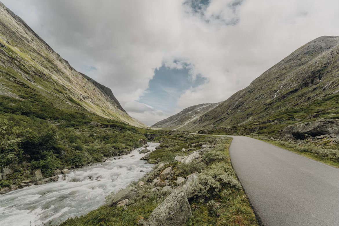 A long empty road beside a gushing river