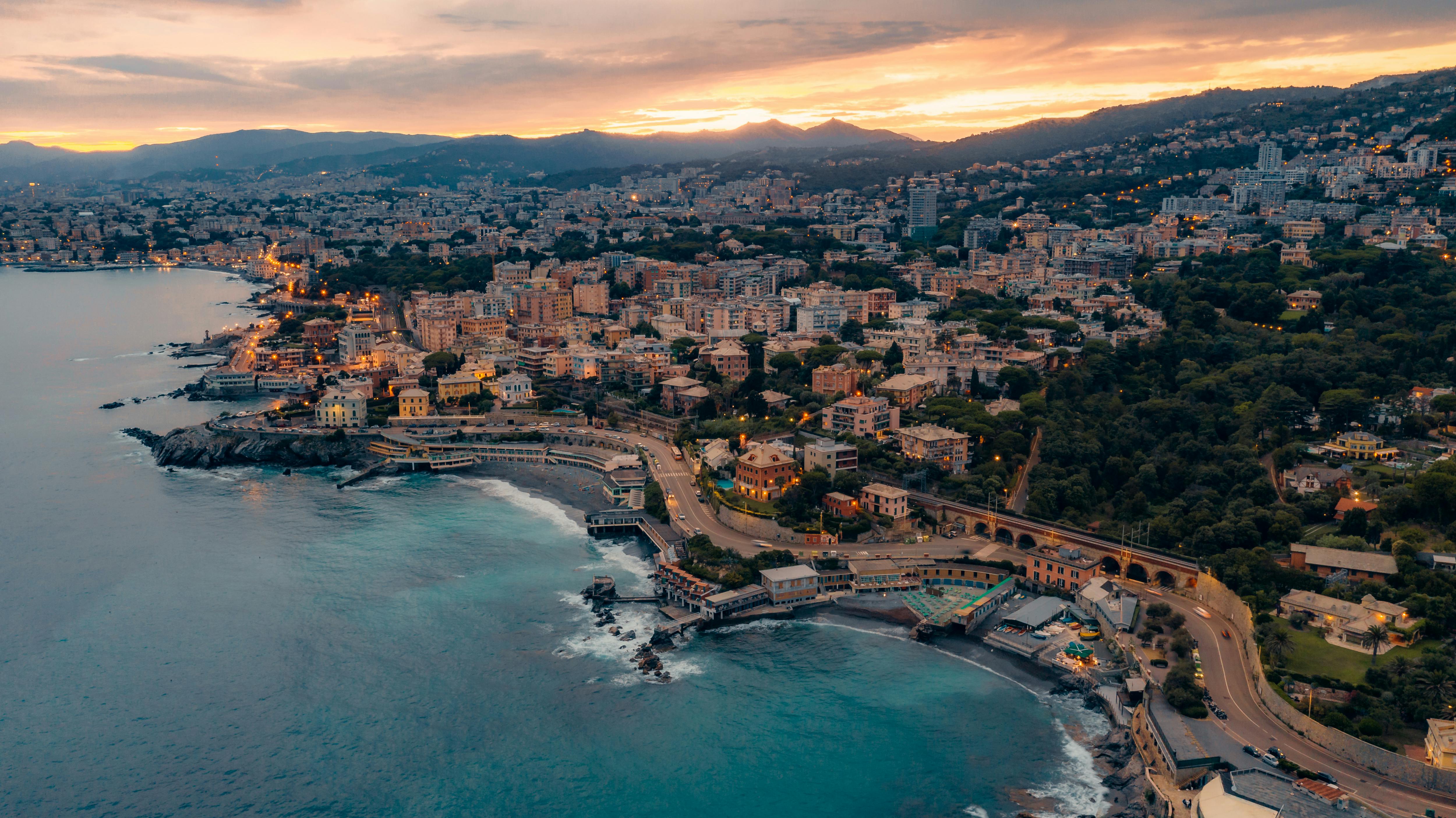 Ein Blick auf Genua im Abendlicht, mit seiner geschwungenen Küste und der beleuchteten Stadt.