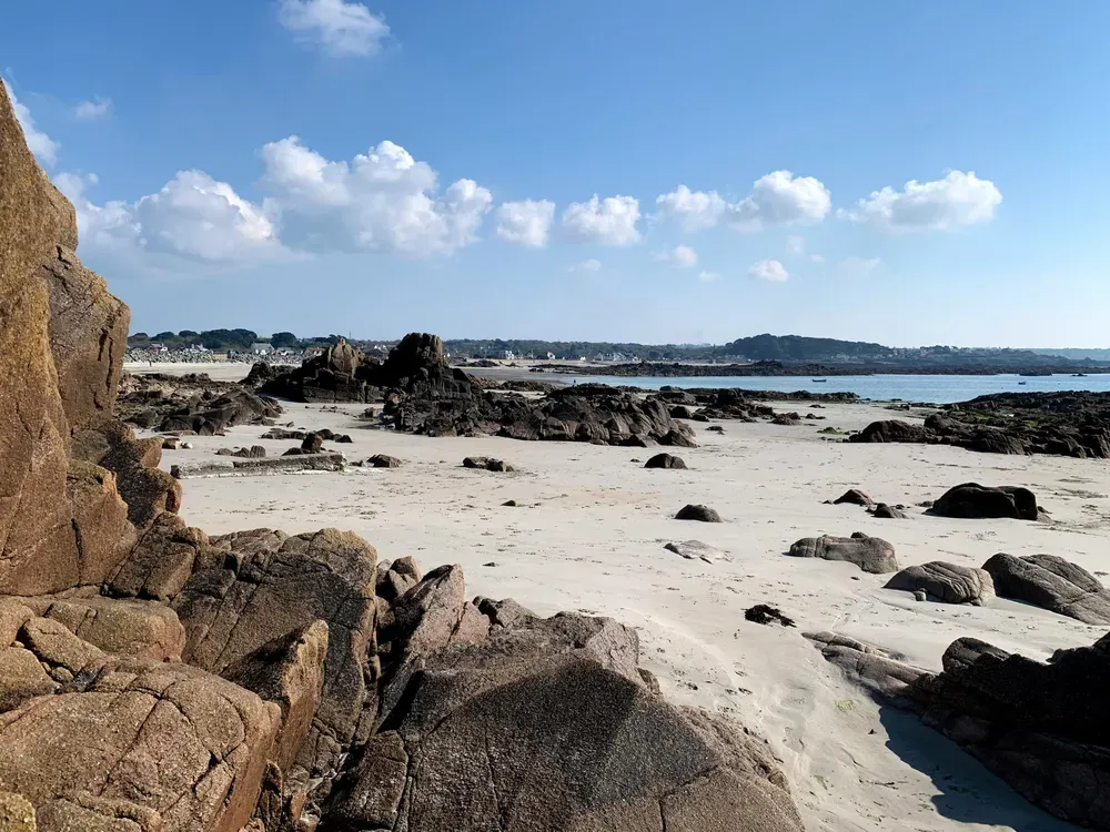 Am Sandstrand Grandes Rocques auf Guernsey liegen Felsen zwischen weißem Pudersand.