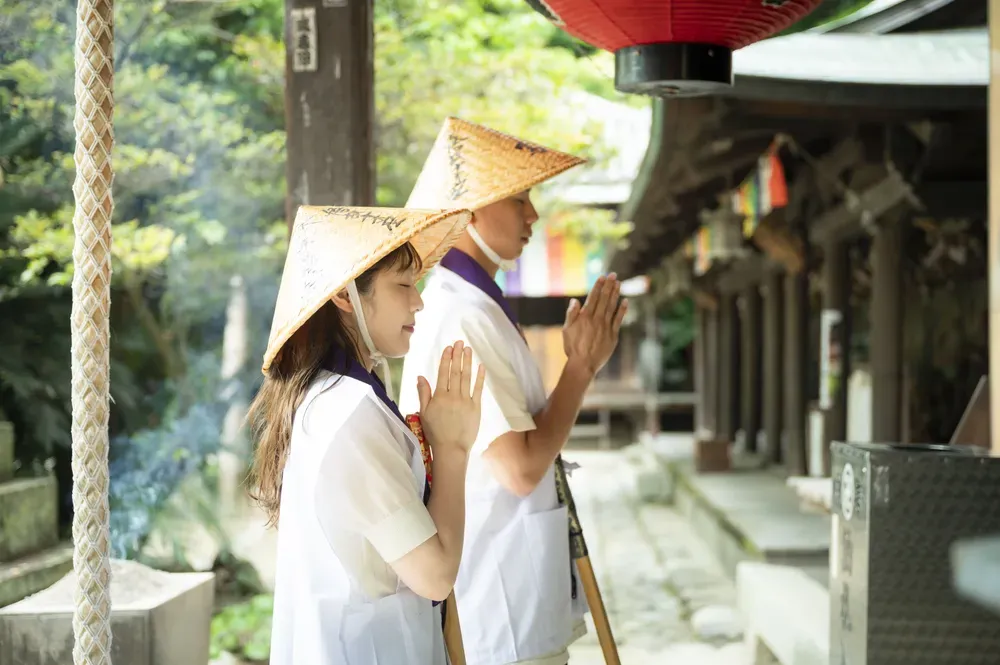 Ein Mann und eine Frau sind von der Seite fotografiert und beten an einem traditionellen japanischen Tempel.
