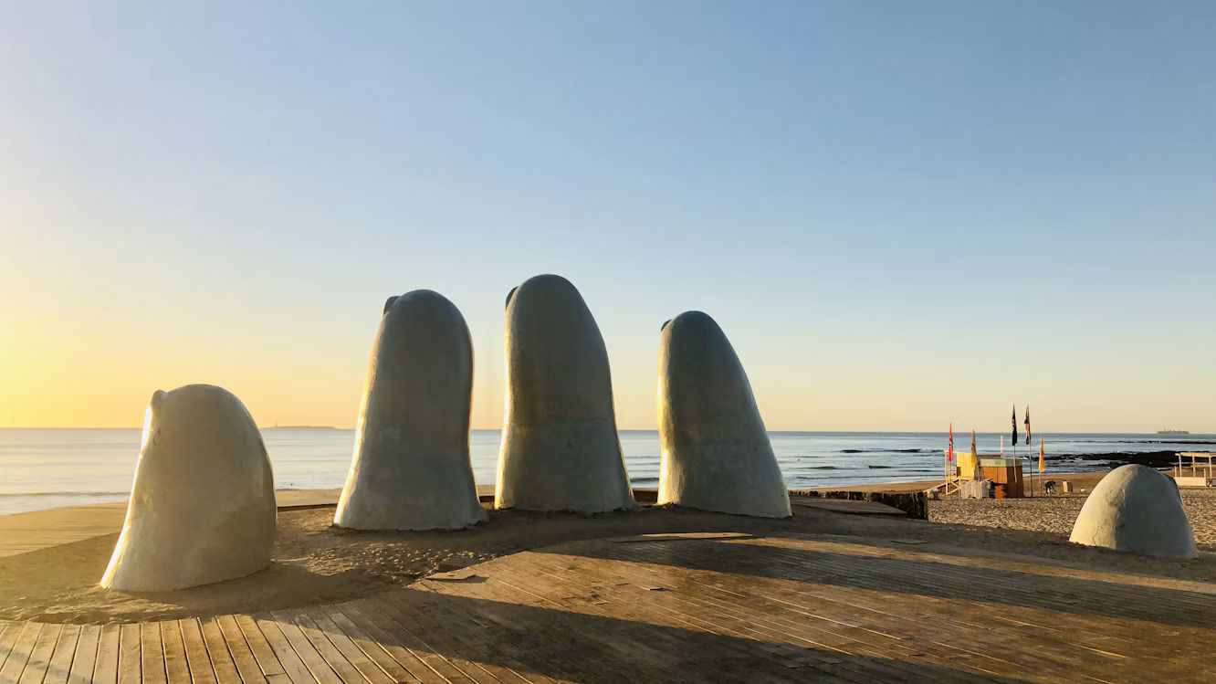 The stone hand of Punta del Este at sunset rising out of the beach
