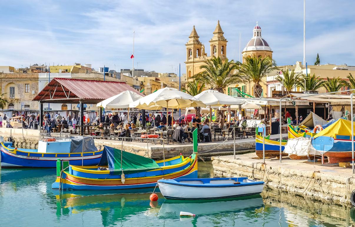Un antiguo pueblo pesquero de Malta con barcas de colores alineadas en el puerto.