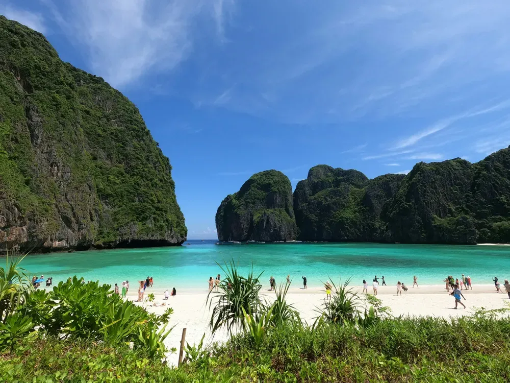 Die Bucht Maya Bay auf Koh Phi Phi, mit weißem Sand, strahlend blauem Meer und begrünten, riesigen Klippen.