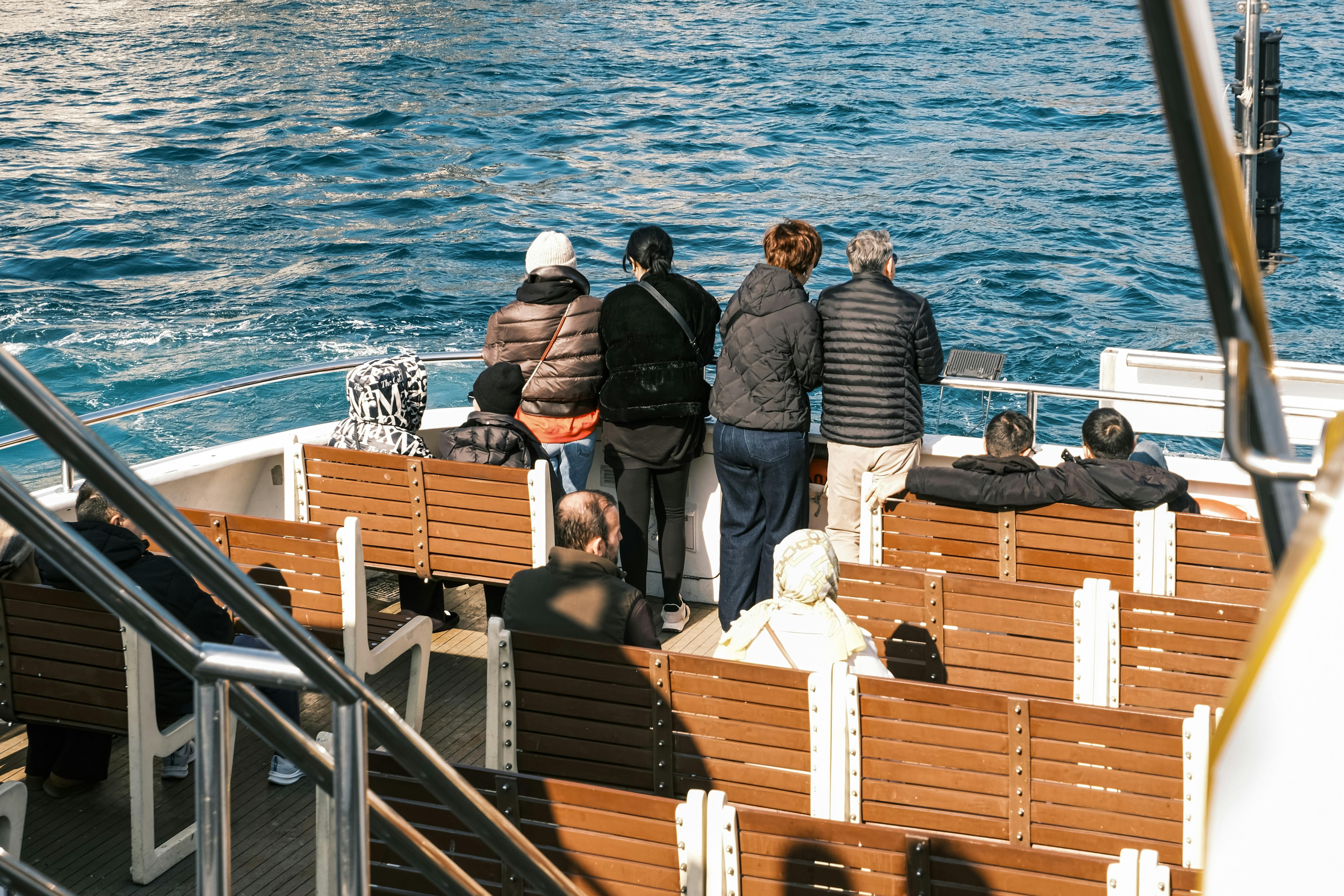 Menschen verschiedenen Alters genießen die Aussicht vom Deck einer Fähre.