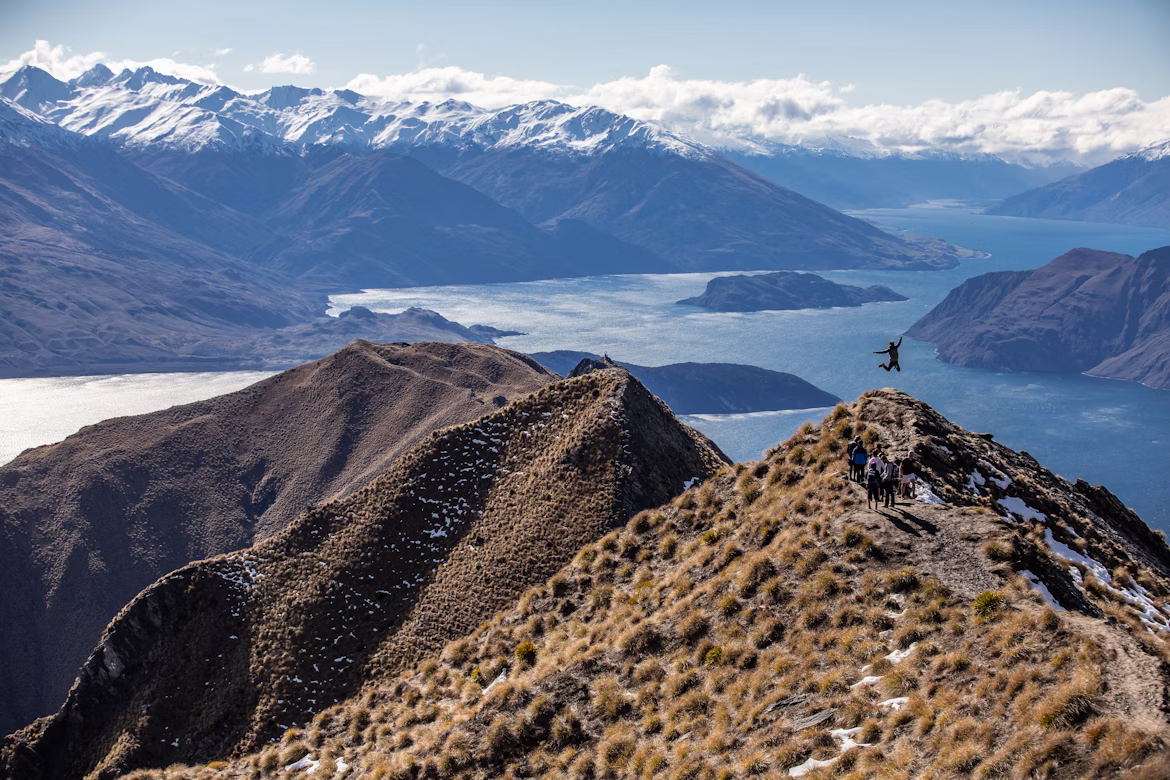 A hiker jumping at the top of Roy's Peak in Wanaka