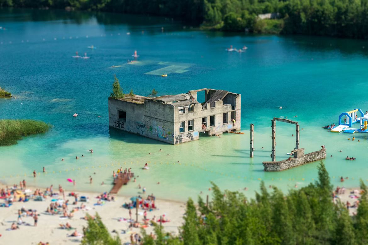 People swimming in an old quarry with an abandoned prison on the water