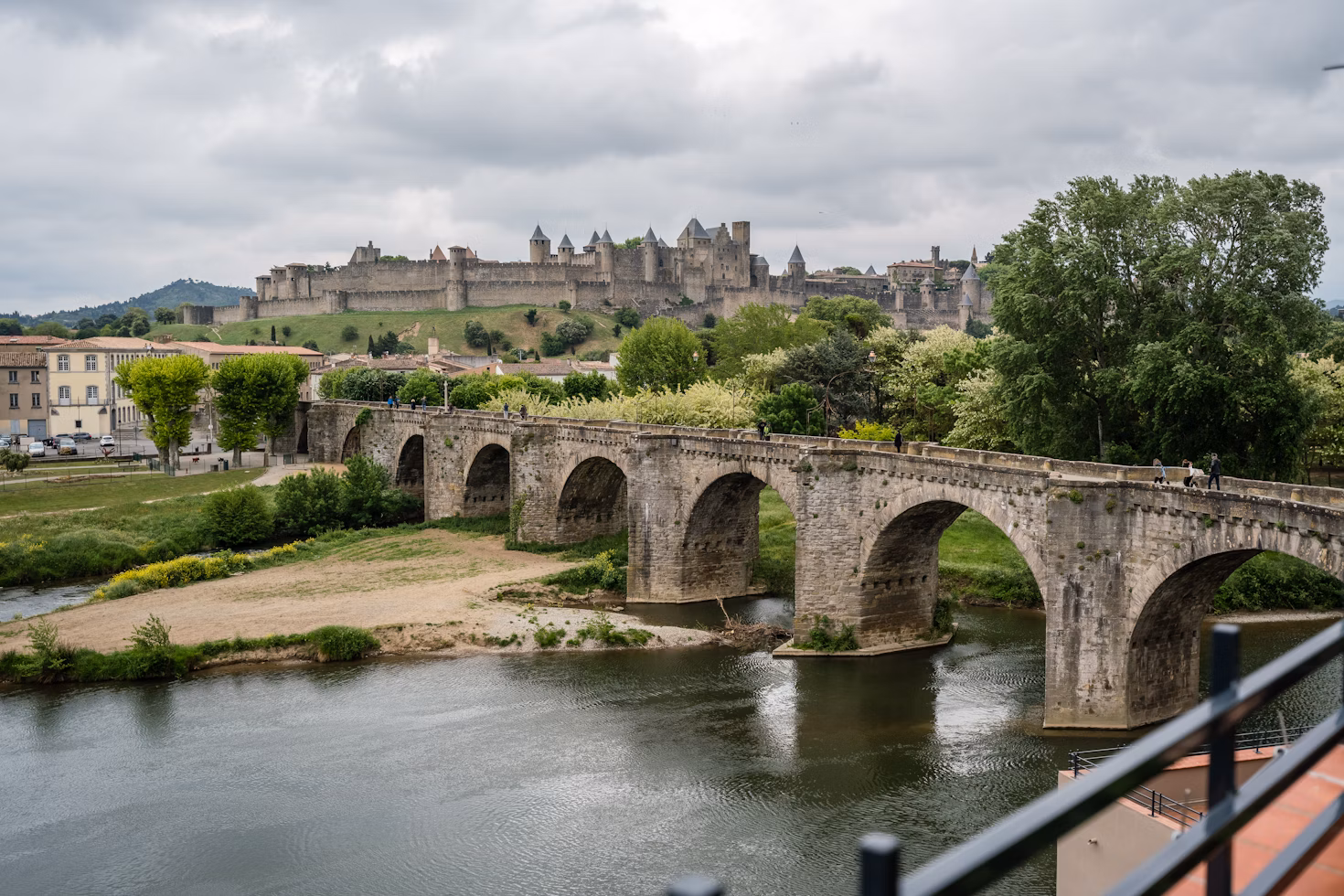 Die Alte Brücke in Carcassonne führt über einen Fluss. Im Hintergrund steht die alte Burg.