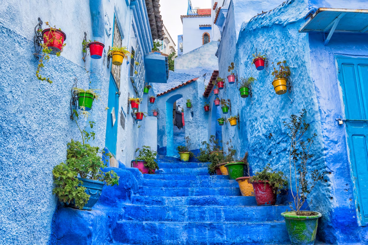 Das Hotel Rue Bin Souaki in Chefchaouen ist mit blauen Wänden und Treppen und bunten bepflanzten Töpfen eine beeindruckende Unterkunft.