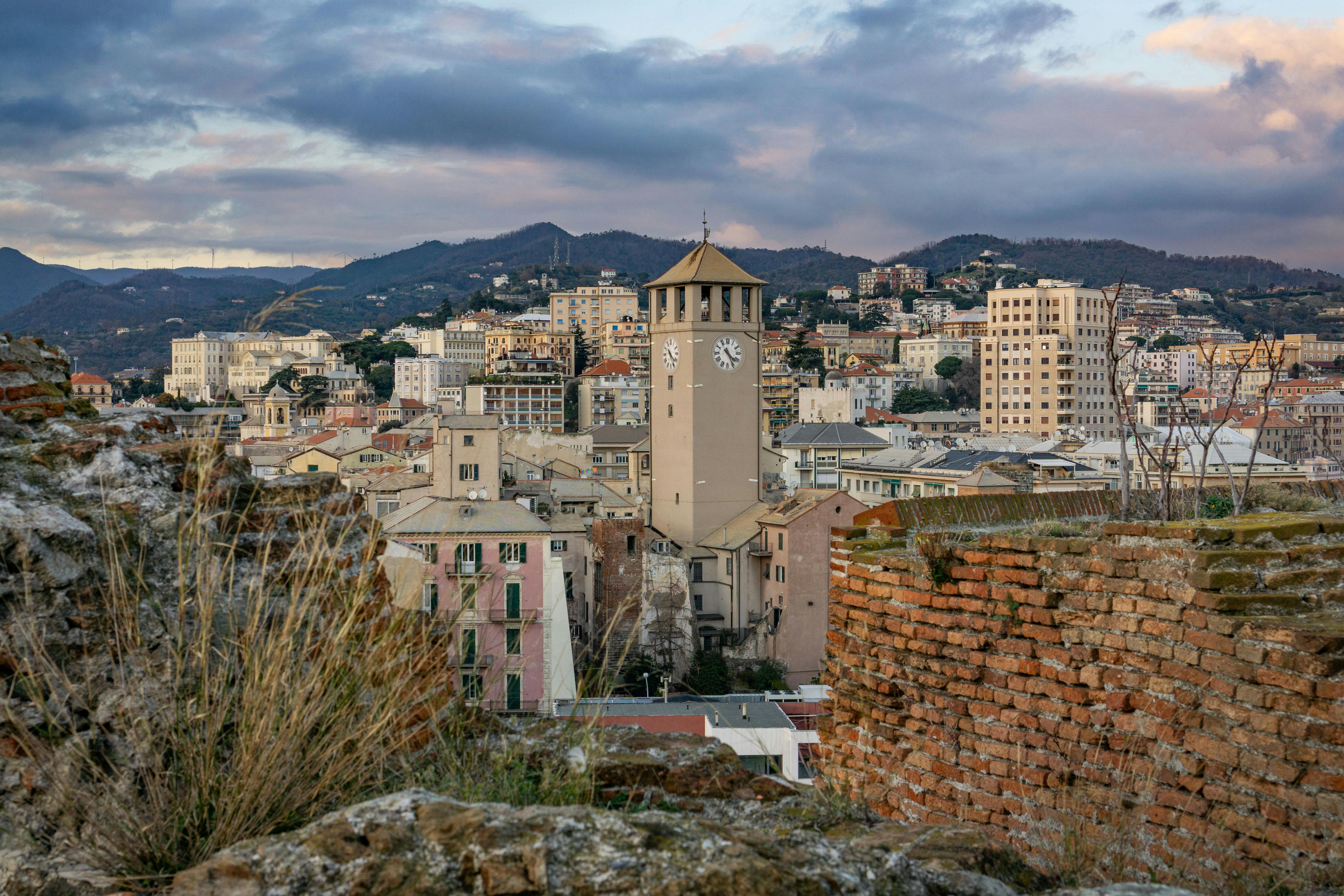 Der Turm von Savona ragt im Abendlicht über den Dächern der Stadt hervor.