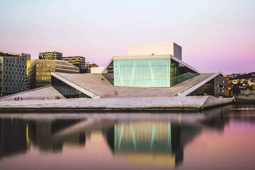 The glass facade of Oslo opera house reflected in the water
