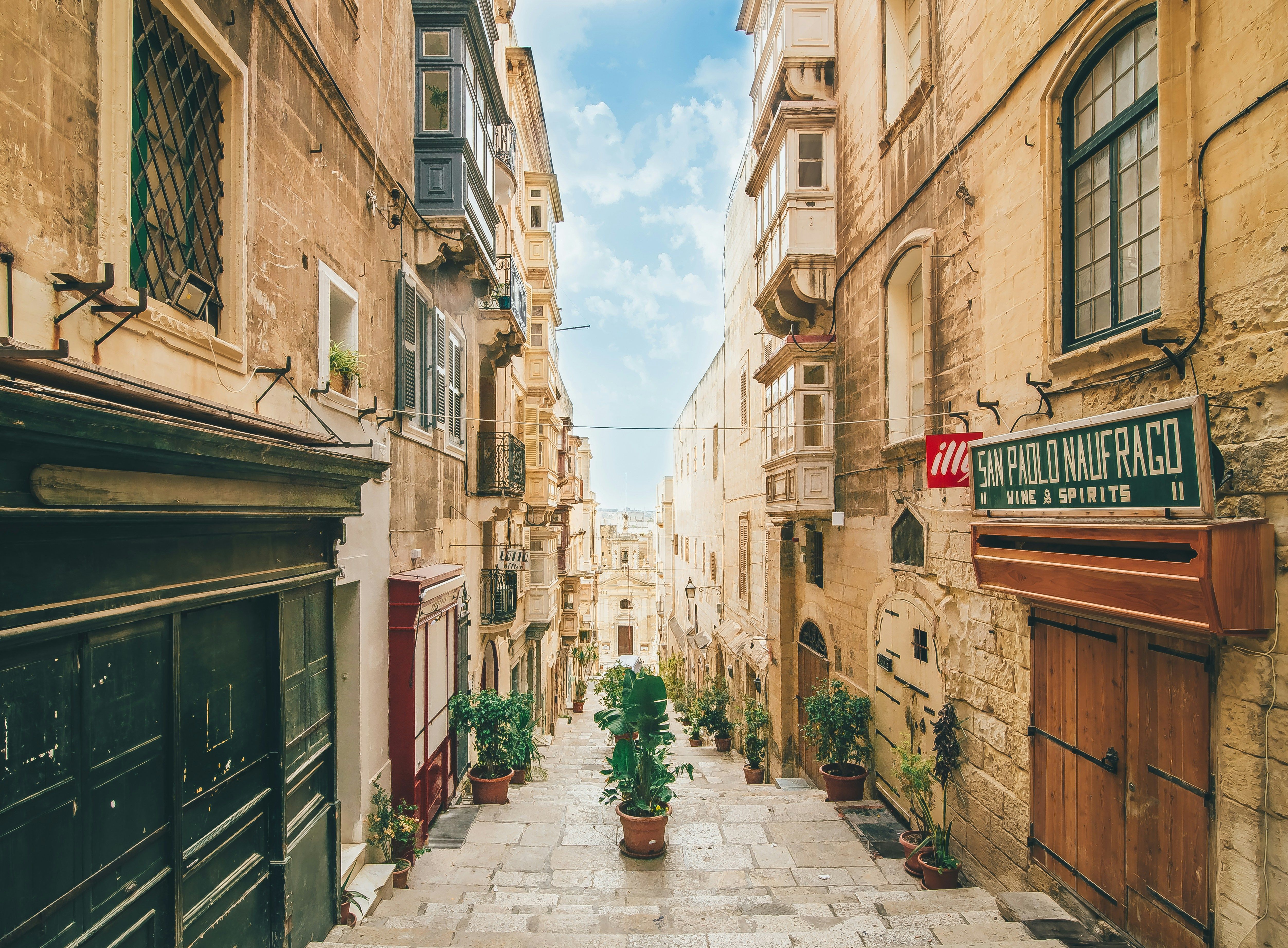 Eine enge Gasse in Valletta, Malta mit charakteristischer Architektur und einem Weg aus Steinfliesen.