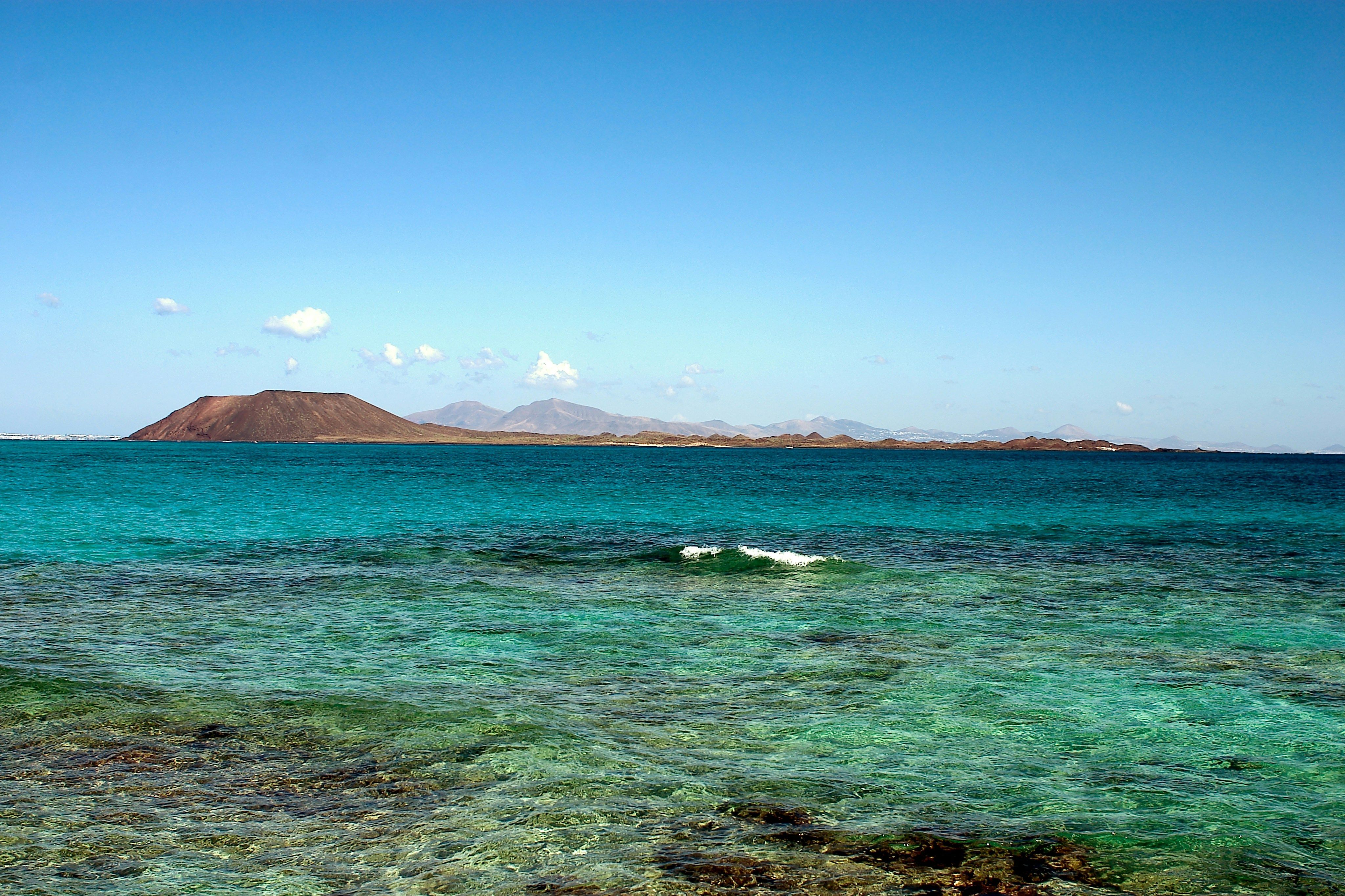À l'horizon, derrière la mer bleue, on aperçoit l'île volcanique de Lobos. La photo a été prise depuis Corralejo.