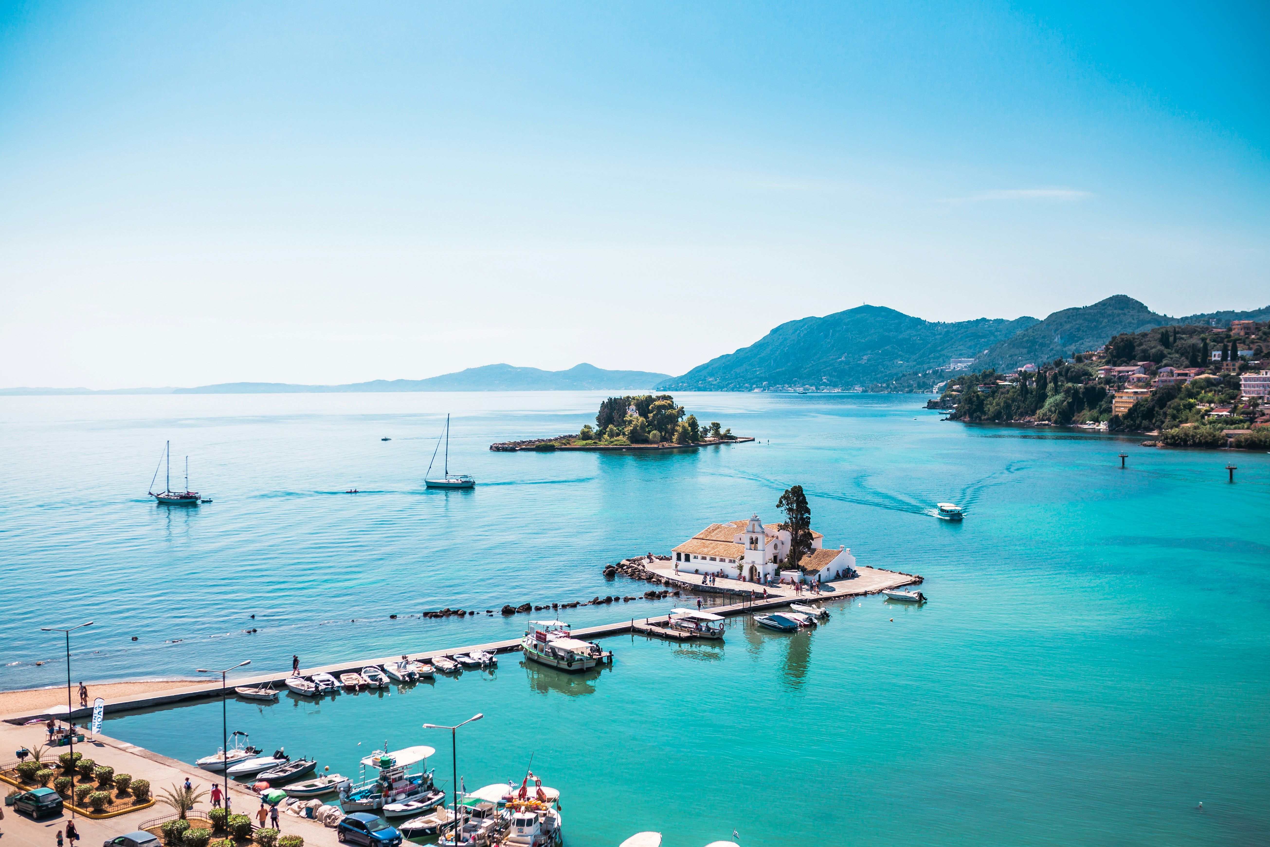 boats docked in the sea in Corfu with hills behind