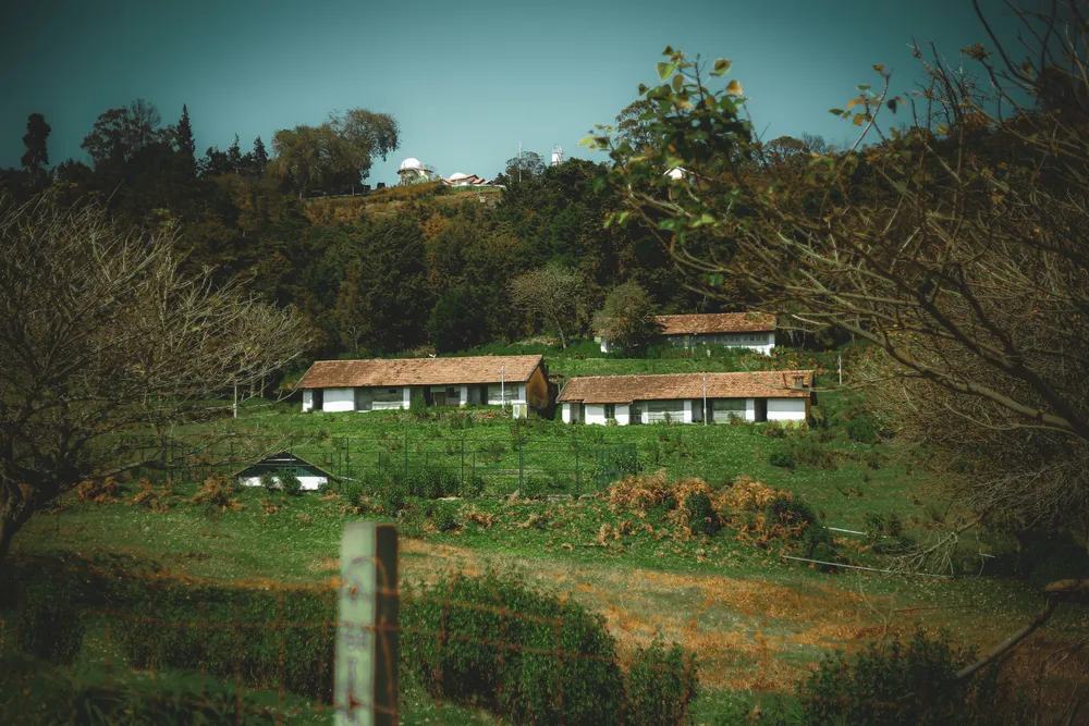 Casas rurales tradicionales rodeadas de campos verdes en una zona montañosa del Dodecaneso