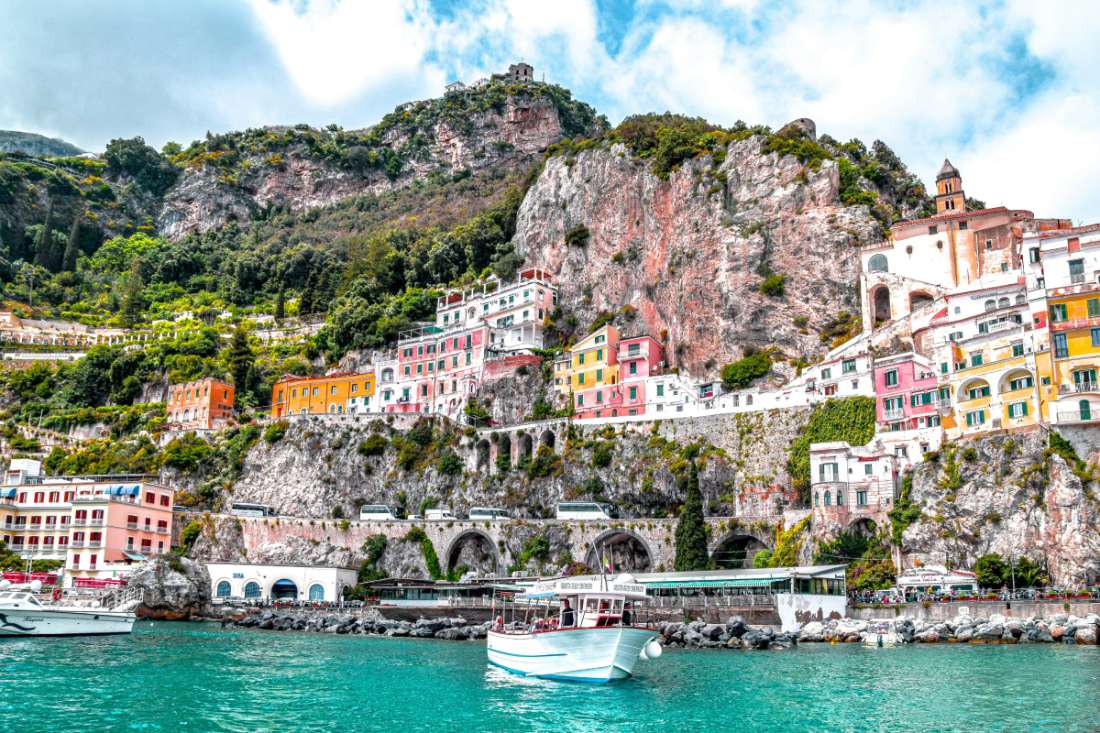 Coloridas casas de Amalfi encaramadas sobre los acantilados, con ferries navegando en aguas turquesas