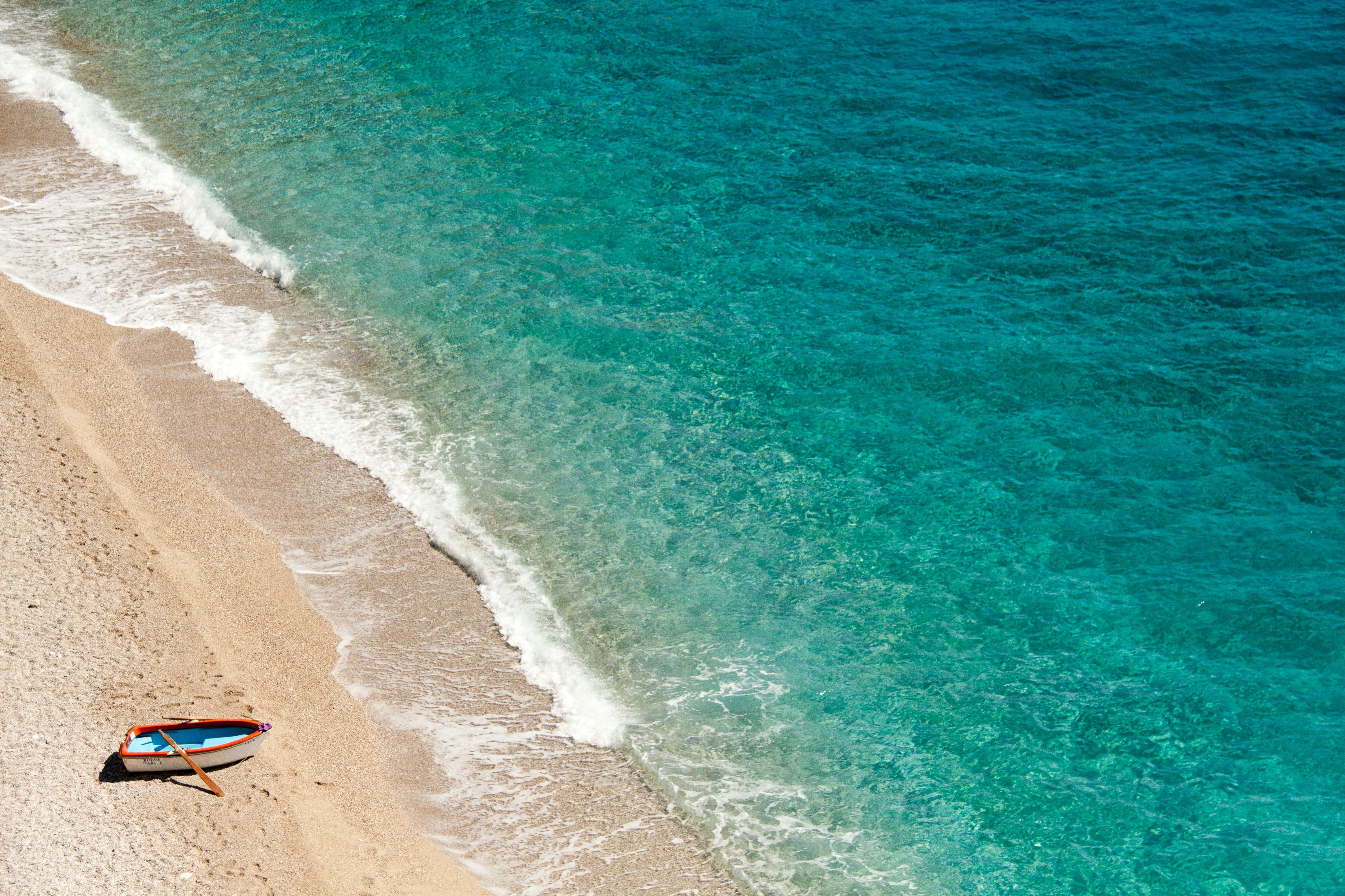 mer turquoise avec petit bateau et plage de sable fin