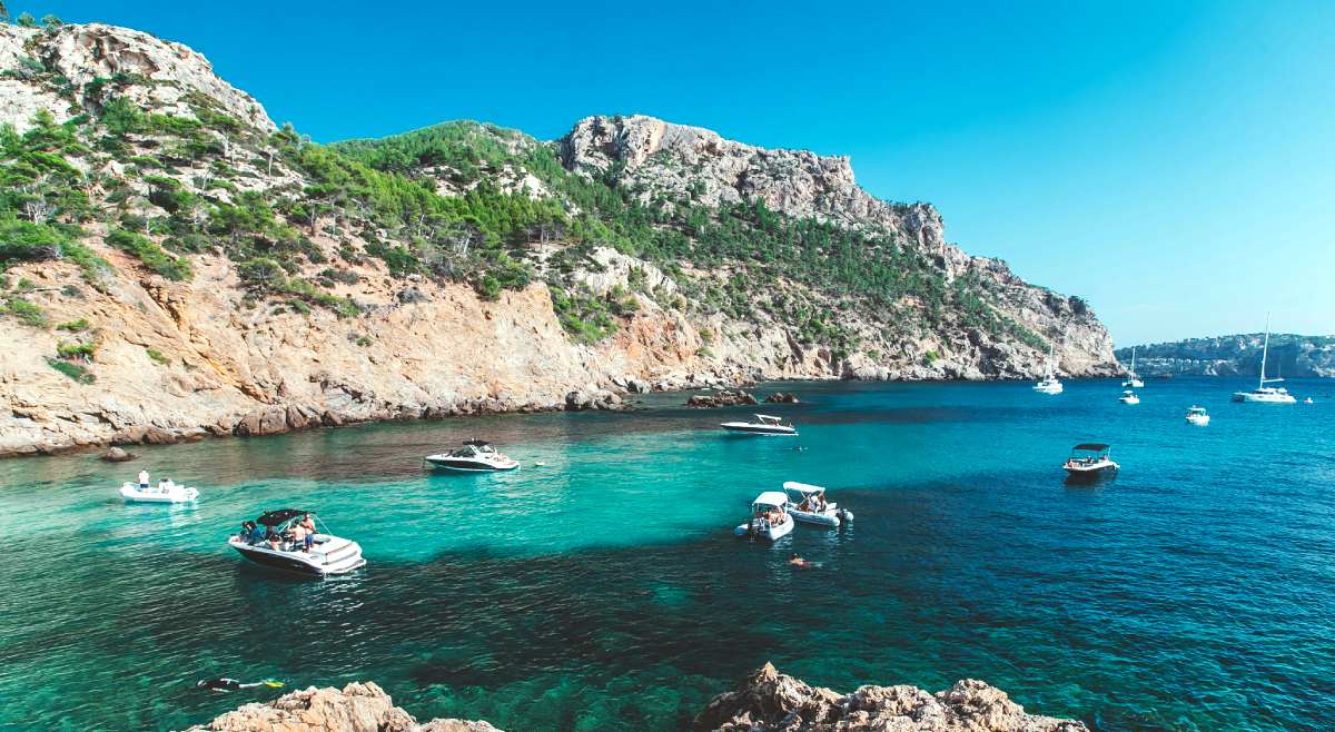 Bahía en Mallorca con barcos fondeados y montañas de la Sierra de Tramuntana