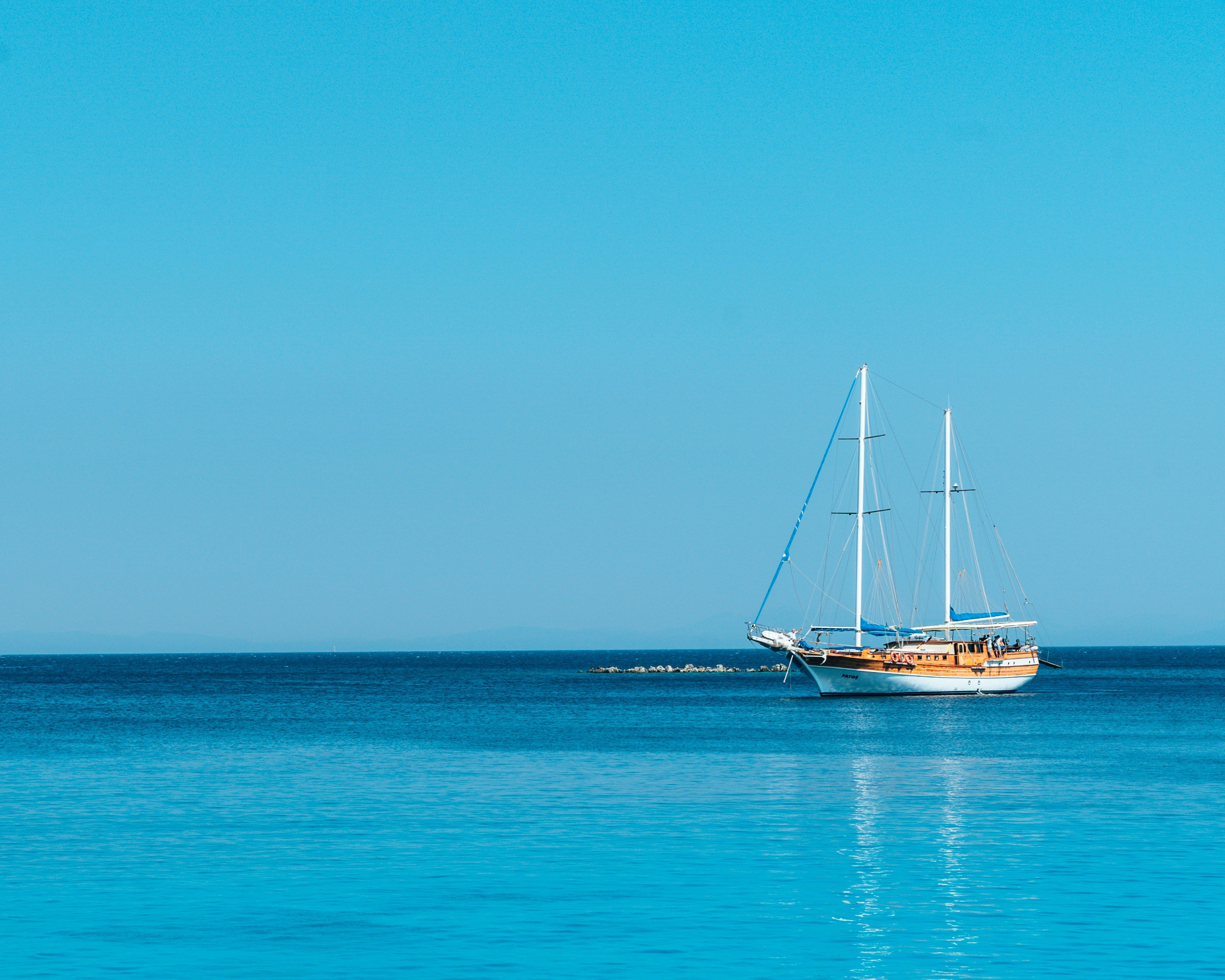 voilier blanc et marron naviguant sur mer bleue claire