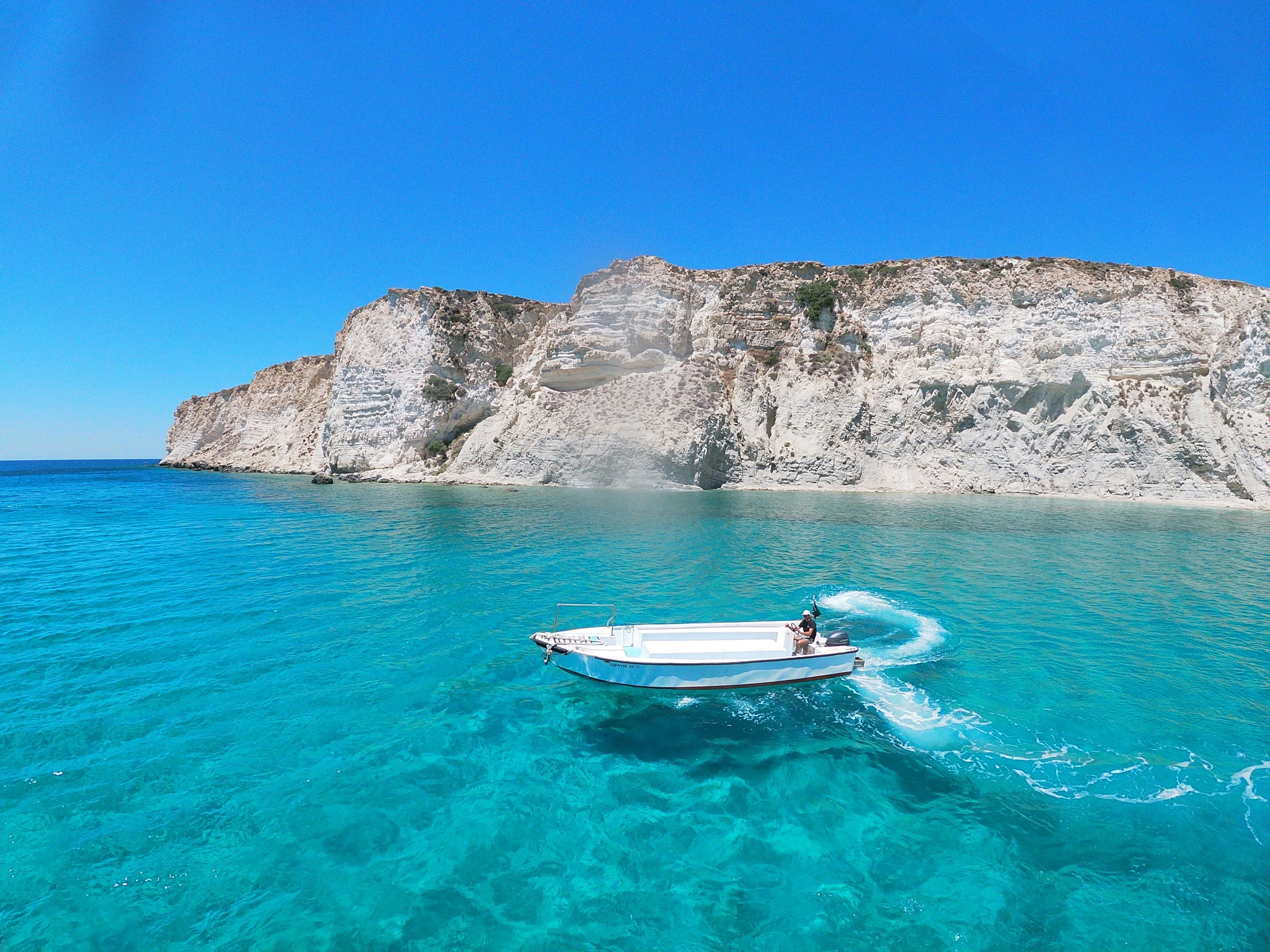eau turquoise bateau blanc falaise au fond