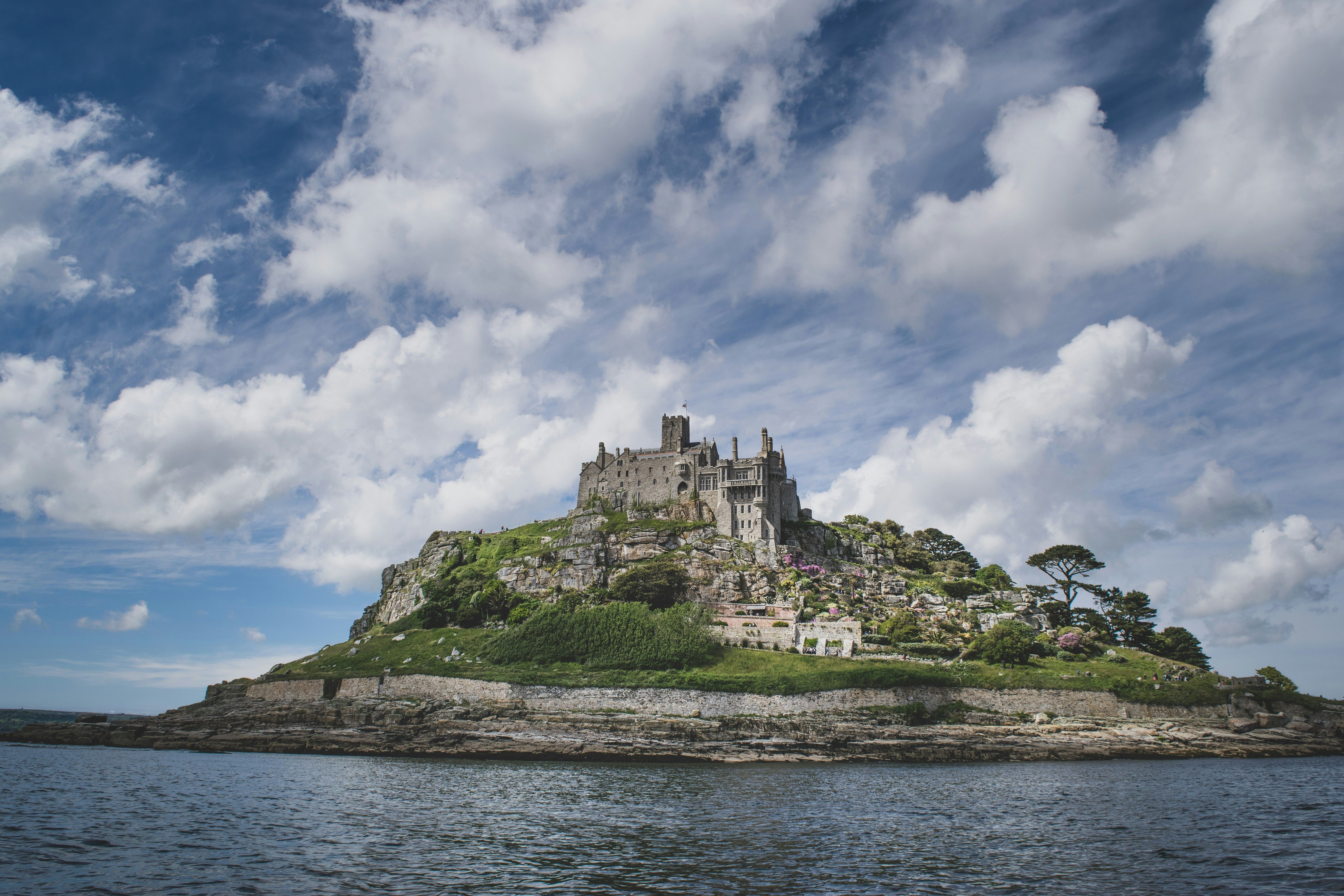 Vom Wasser aus sieht man St Michael’s Mount, eine Gezeiteninsel in Cornwall. Sie ragt majestätisch aus dem Wasser hervor, der Himmel ist leicht bewölkt.