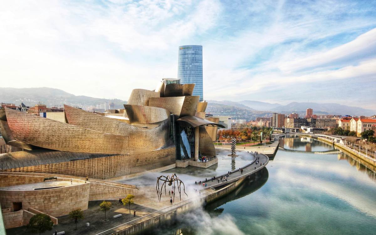 Museo Guggenheim de Bilbao reflejado en la ría con el cielo despejado y tonos invernales.