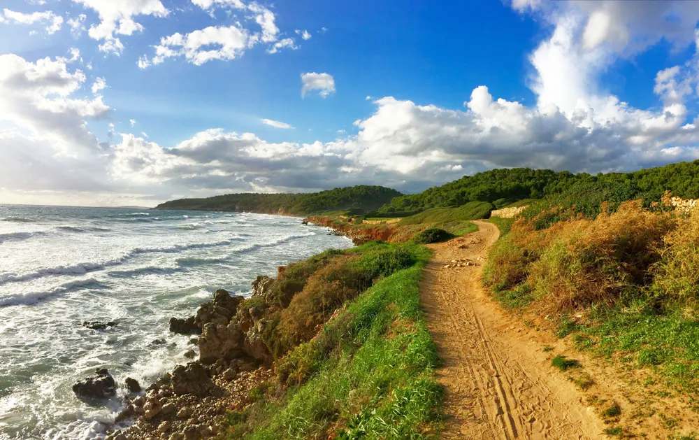 Pequeñas embarcaciones en una cala escondida de Menorca con acantilados y agua turquesa