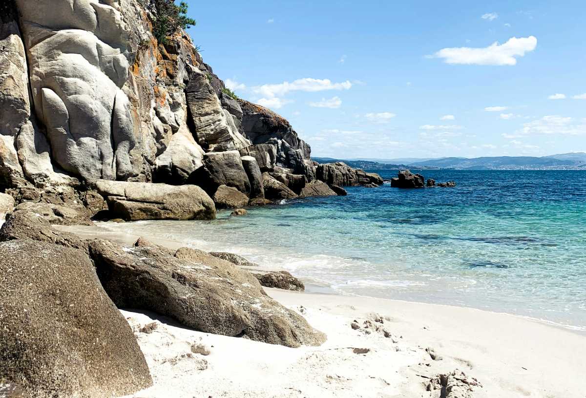 Cala escondida en las Islas Cíes con grandes formaciones rocosas y agua transparente, perfecta para quienes buscan tranquilidad y paisajes naturales.