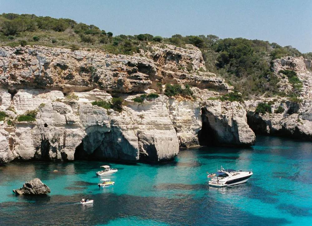 Barcos anclados en las aguas cristalinas de Cala Macarella en Menorca