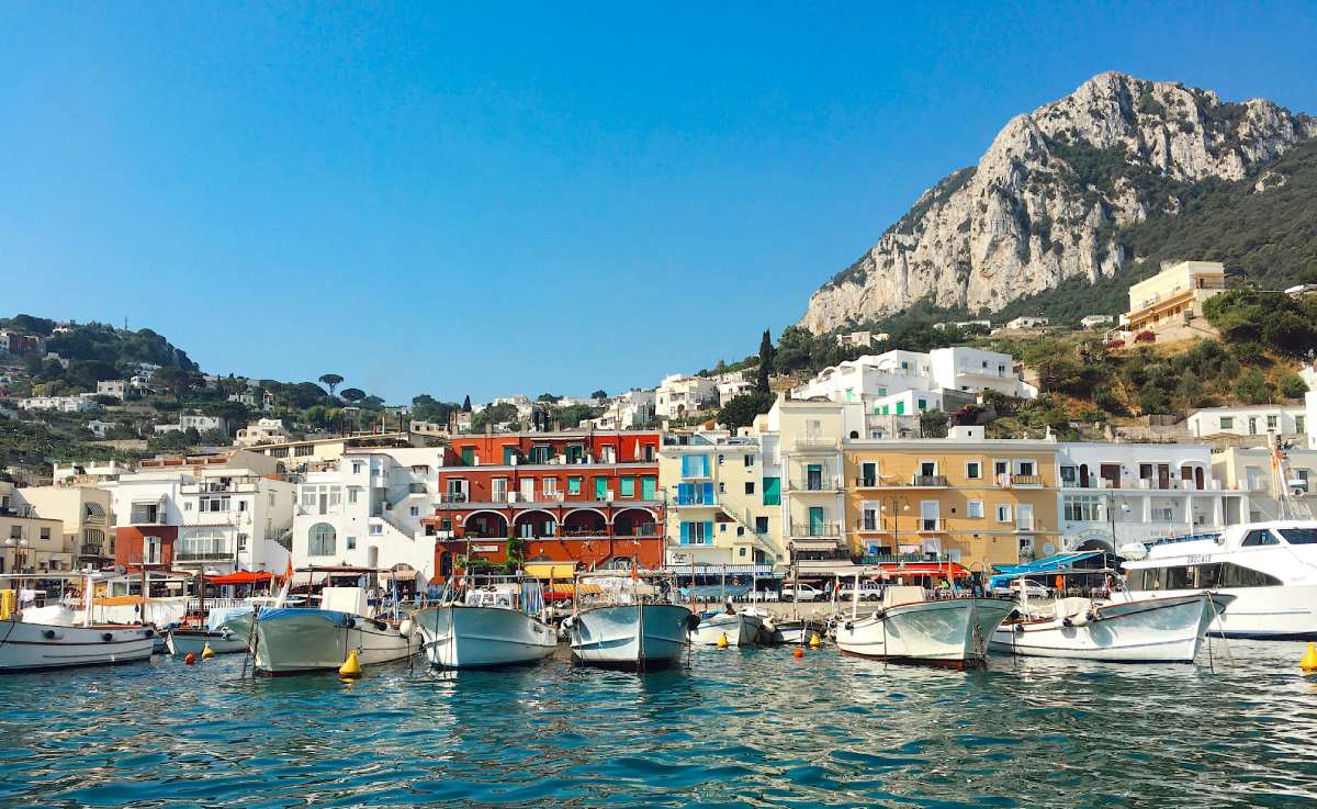 Puerto de Capri con fachadas coloridas y embarcaciones frente a los acantilados