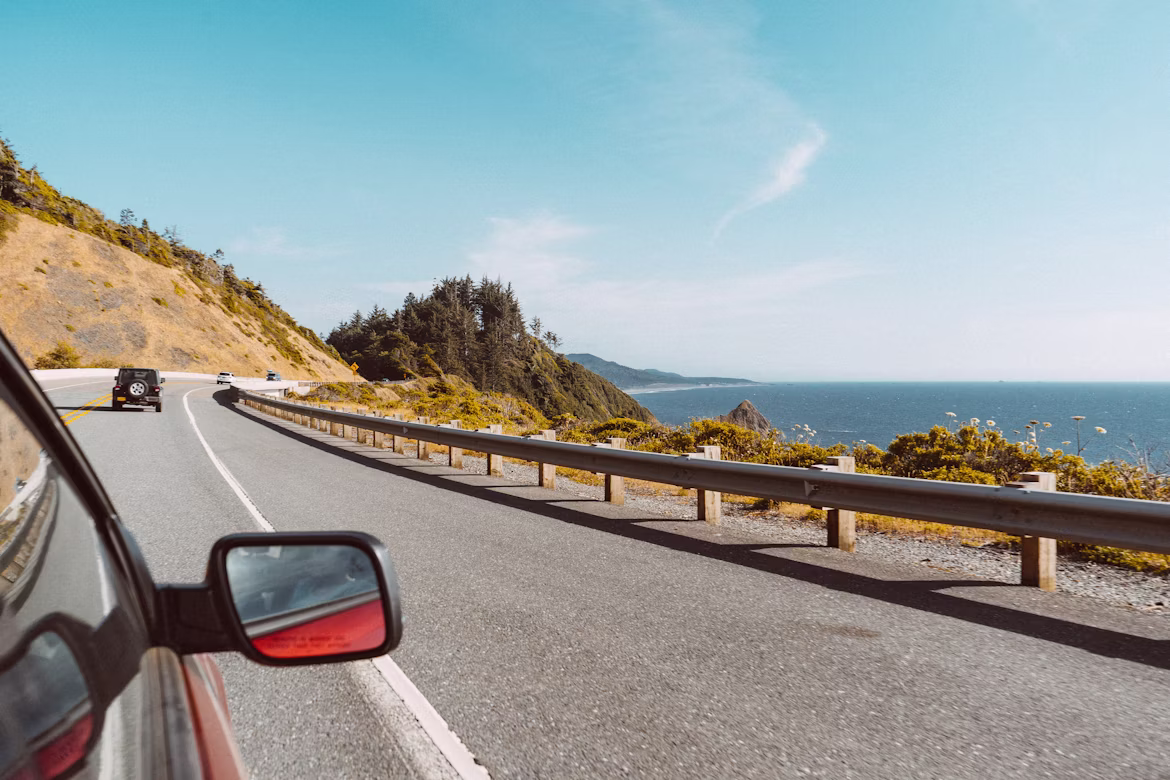 cars driving along a road next to the sea
