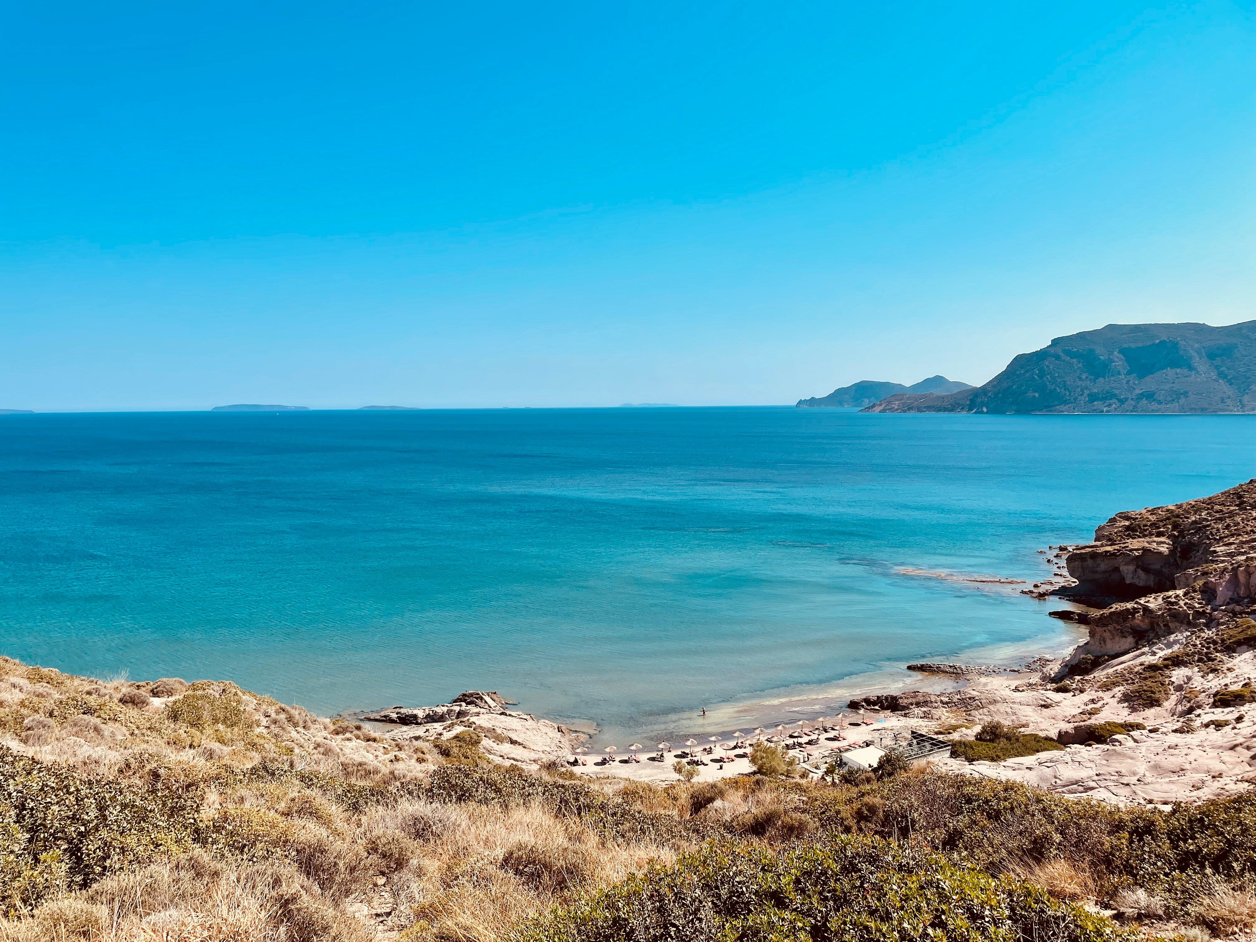 umbrellas on a sandy bay surrounded by mountains