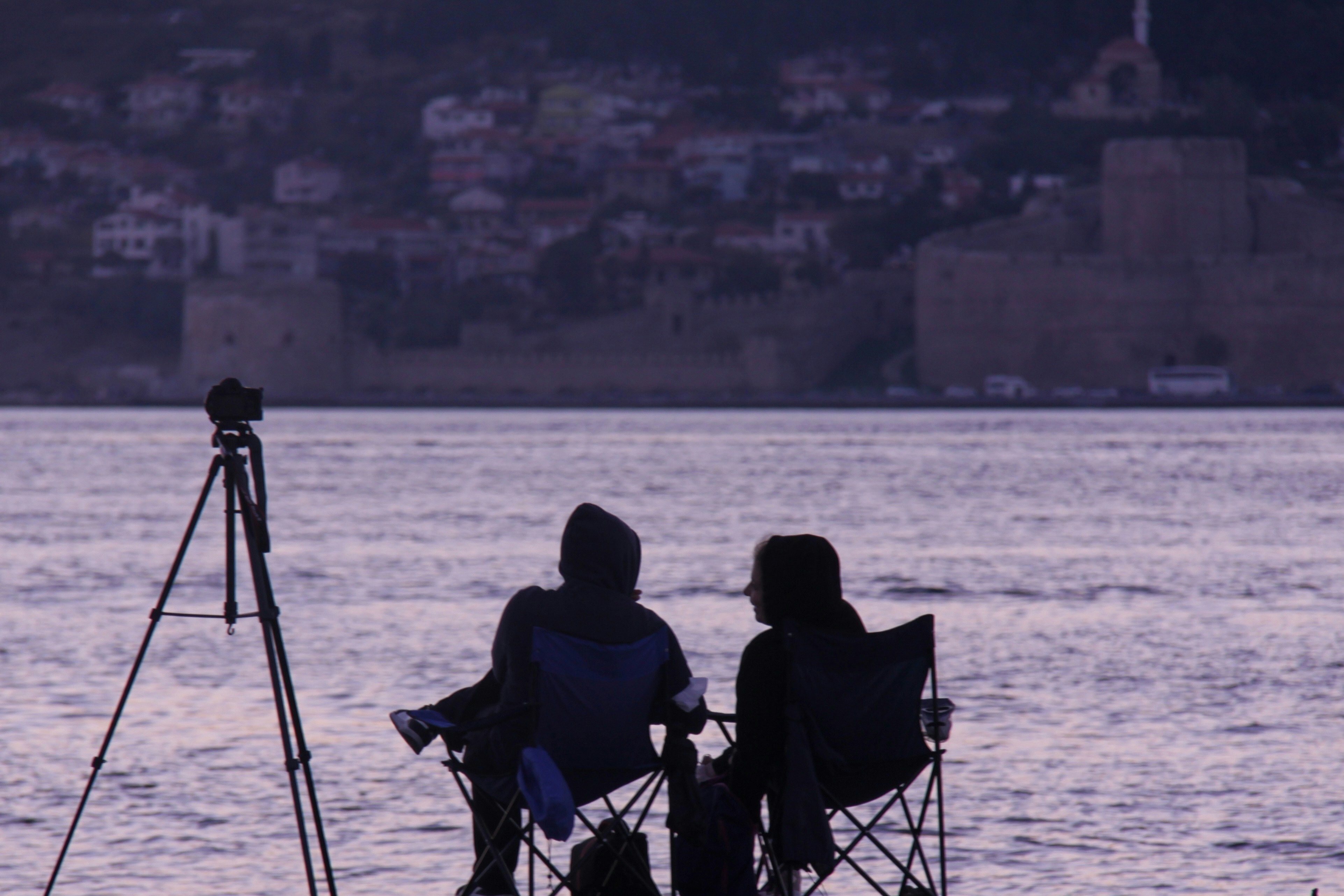 deux personnes avec une camera devant de l'eau