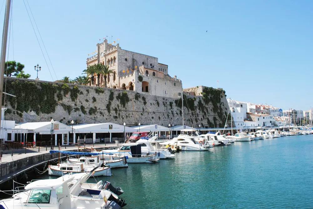 Puerto de Ciutadella en Menorca con el castillo de fondo y barcos atracados