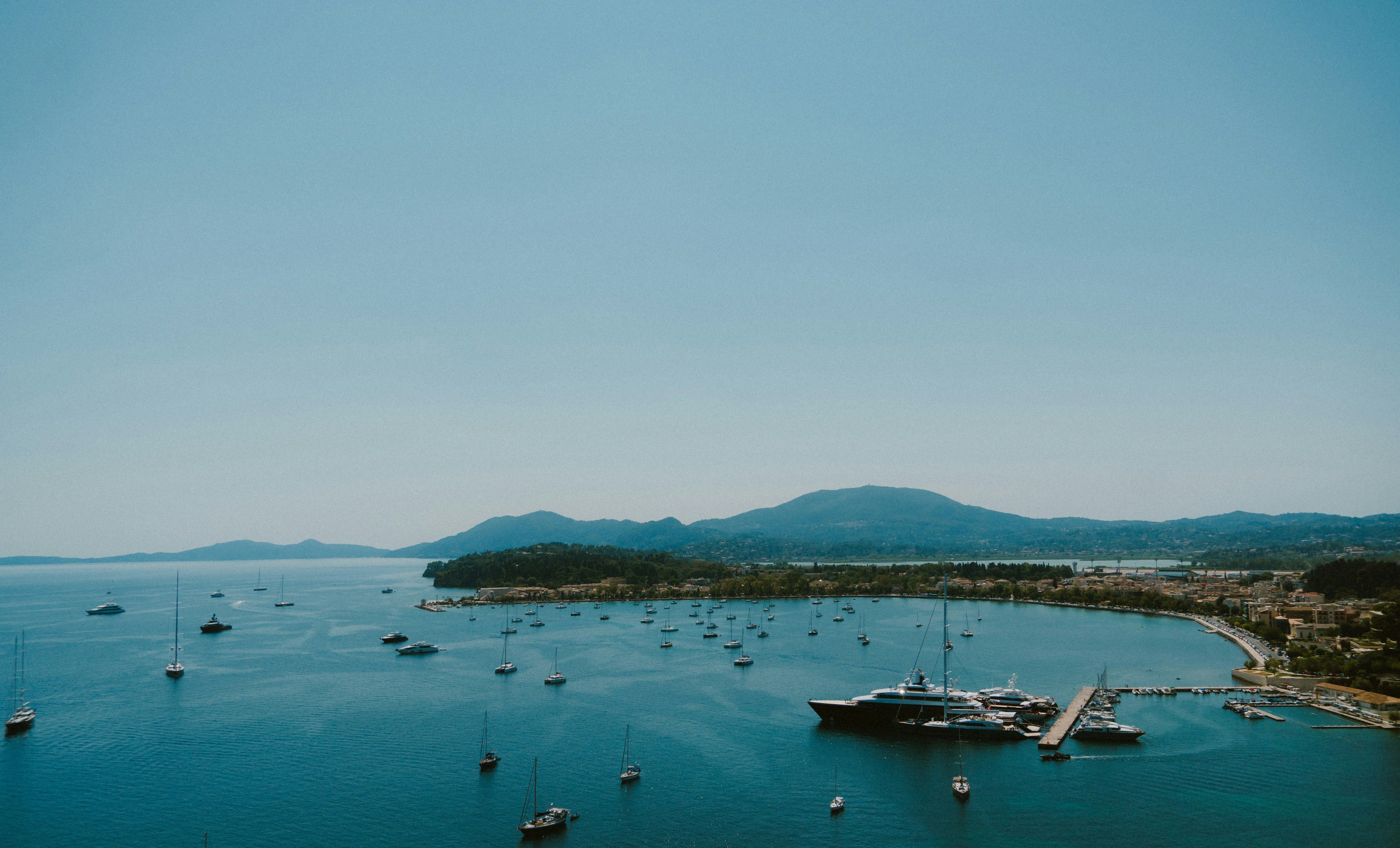 marina avec eau bleu bateaux et montagnes au fond