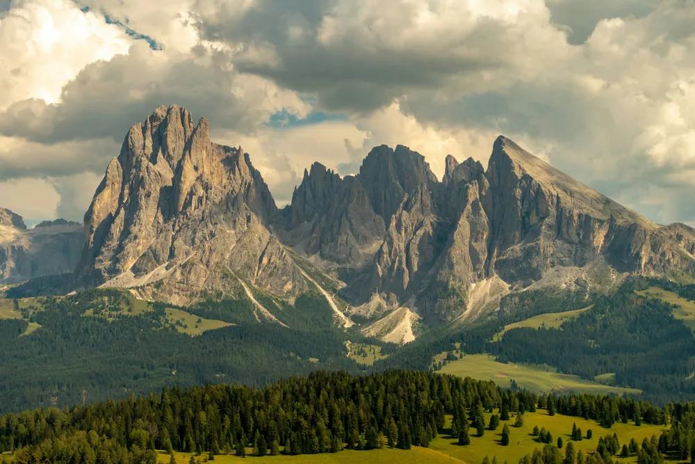 Picos afilados de los Dolomitas sobre un valle verde con bosque y praderas