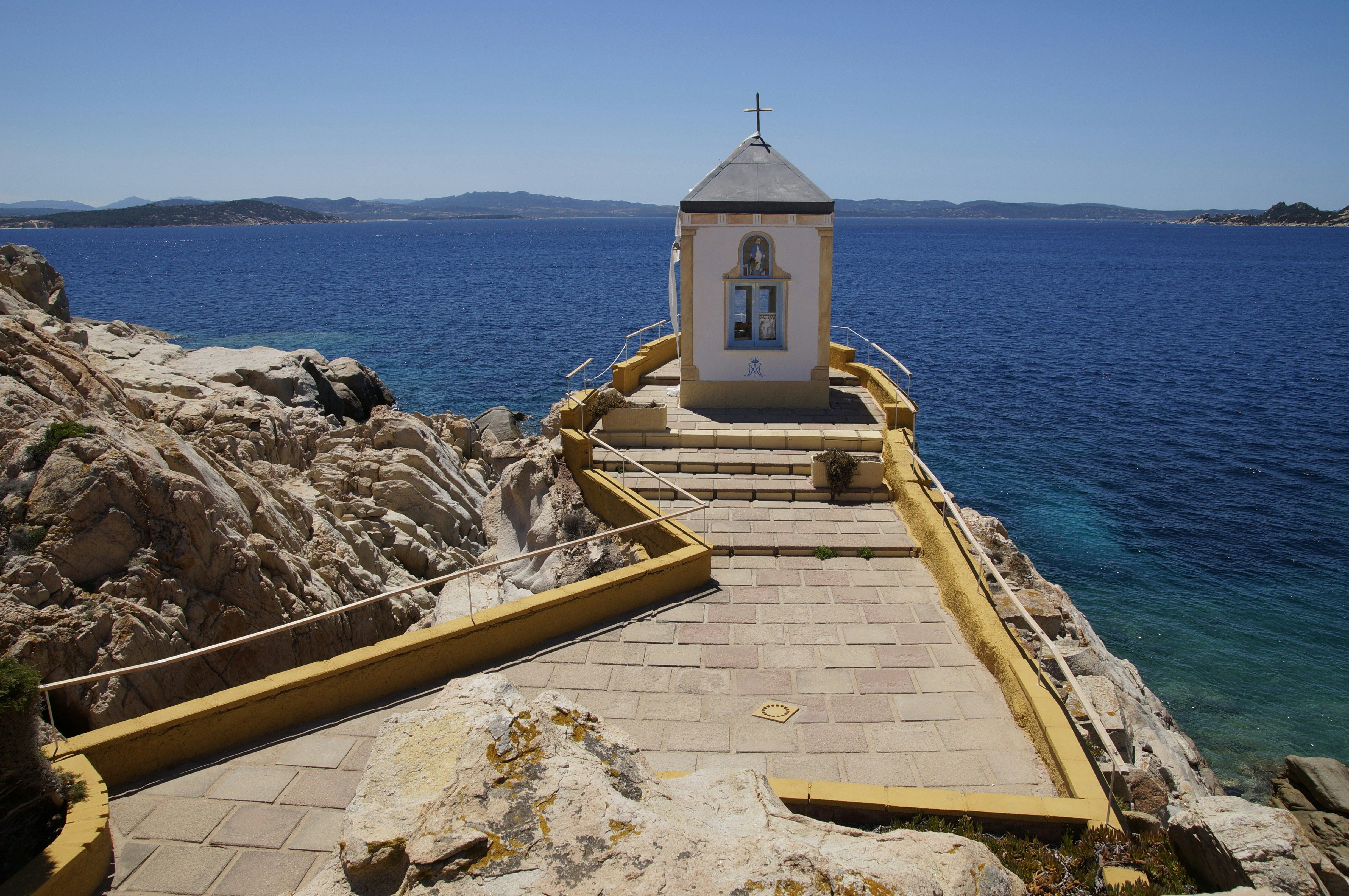 eglise jaune sur falaise rocheuse et mer au fond
