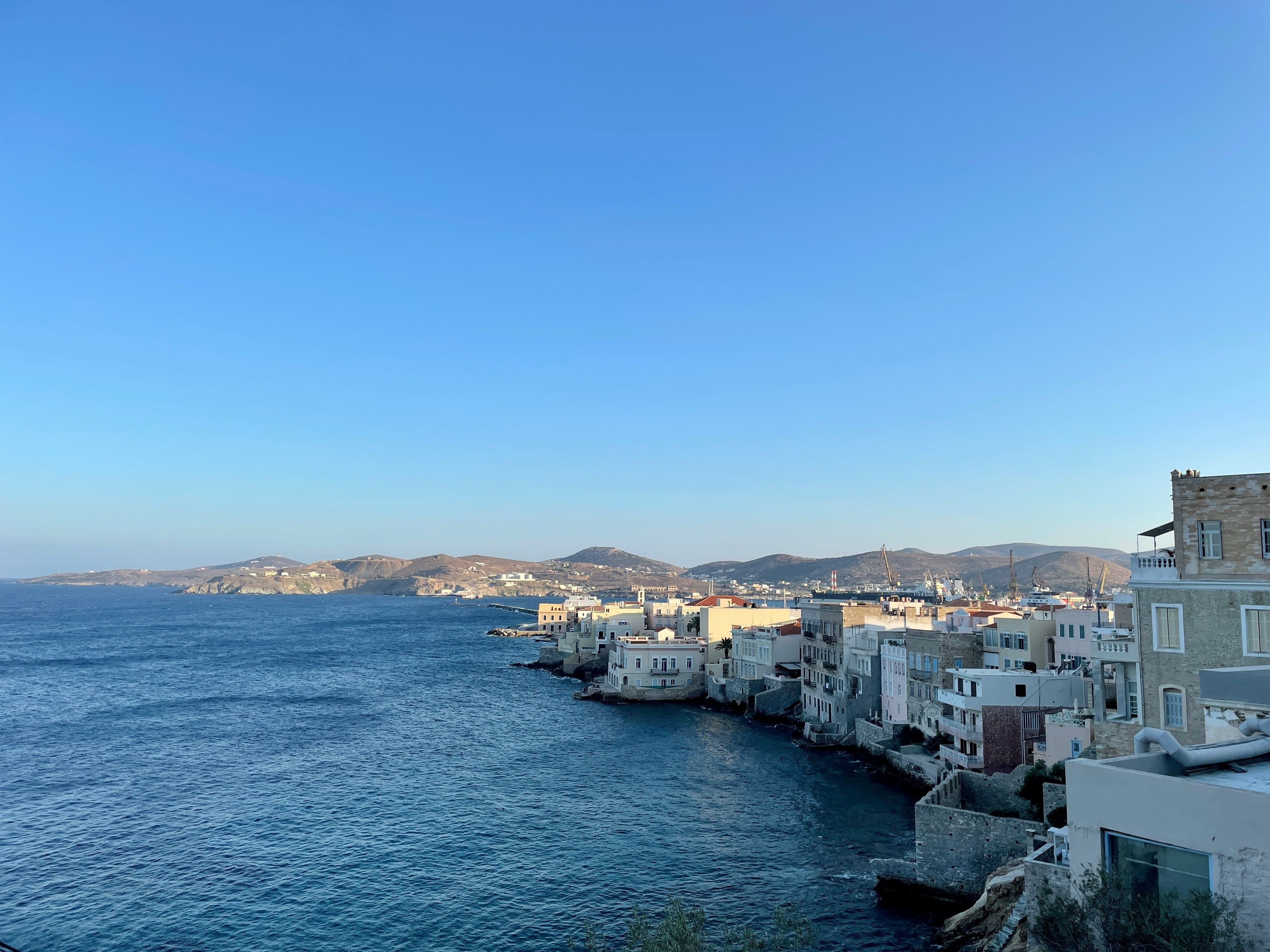 white buildings by the sea with mountains in background