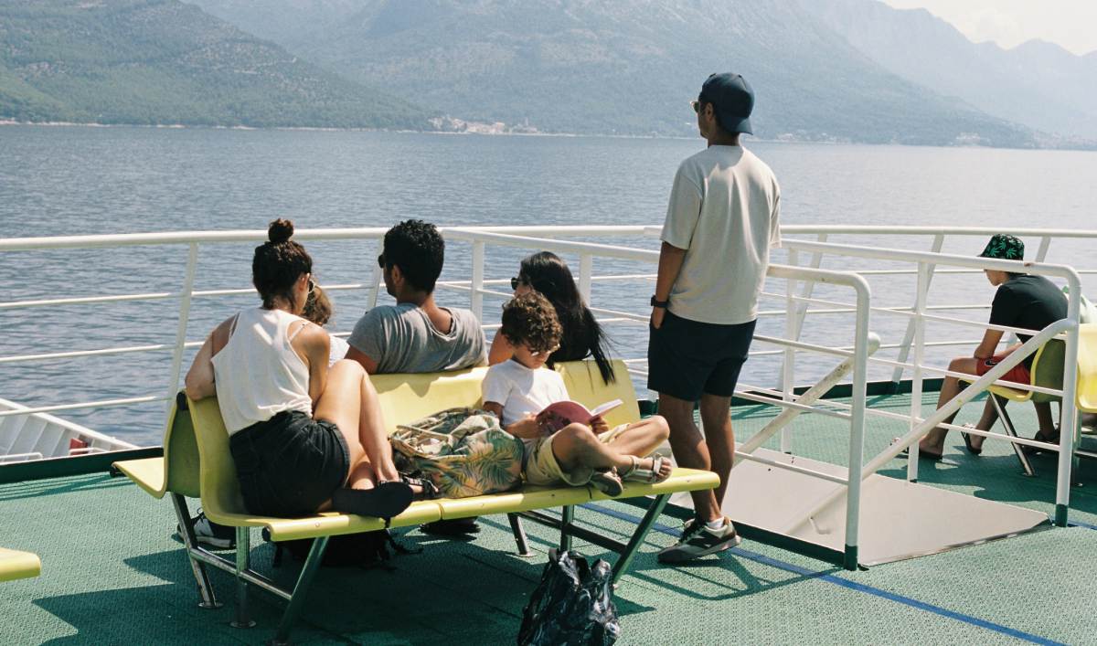 Familia viajando en ferry hacia Ibiza, descansando en la cubierta con vistas a la costa mediterránea.