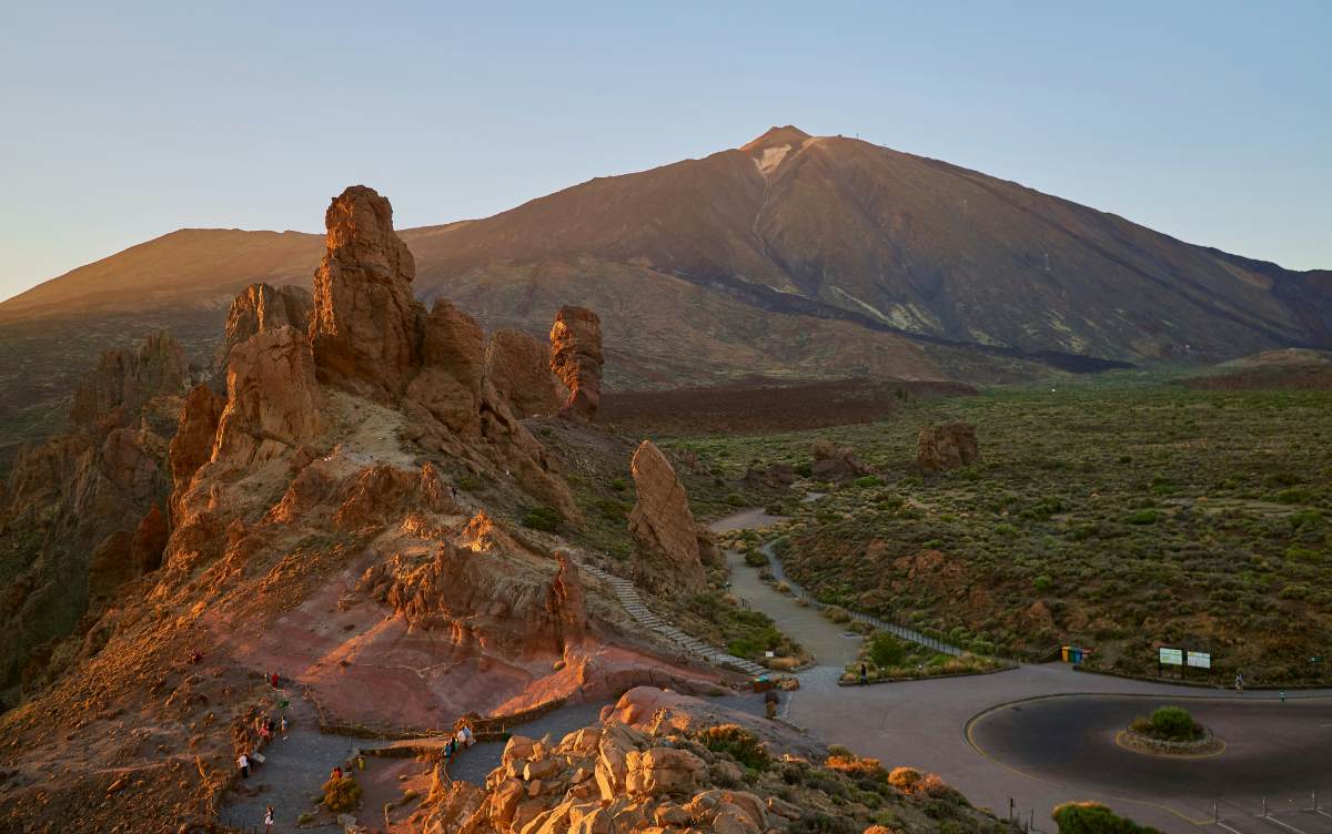 Paisaje volcánico con el Teide al fondo iluminado por el sol del atardecer en Tenerife.