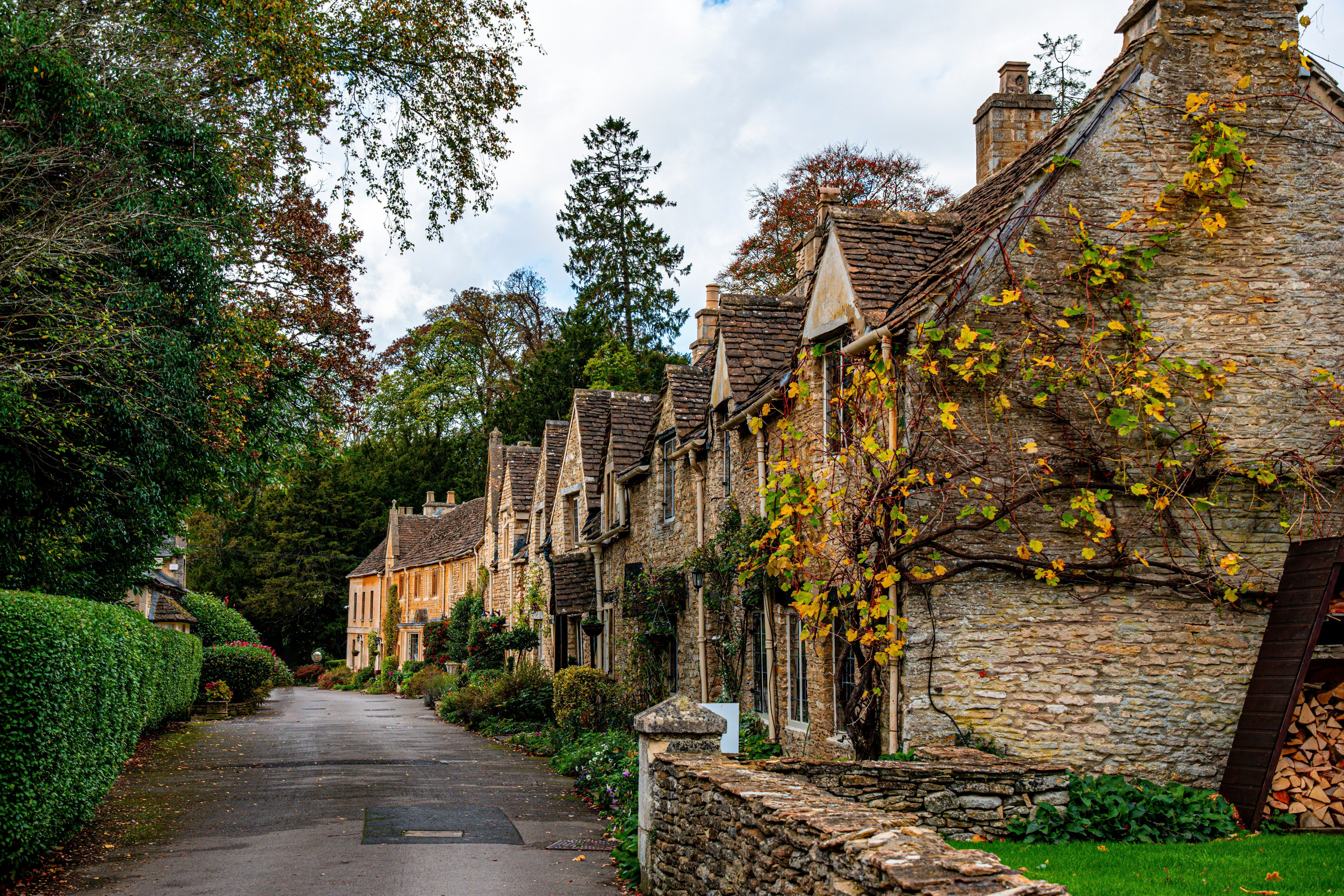 Die Kalksteinhäuser der Cotswolds in England stehen nebeneinander an einem Weg.