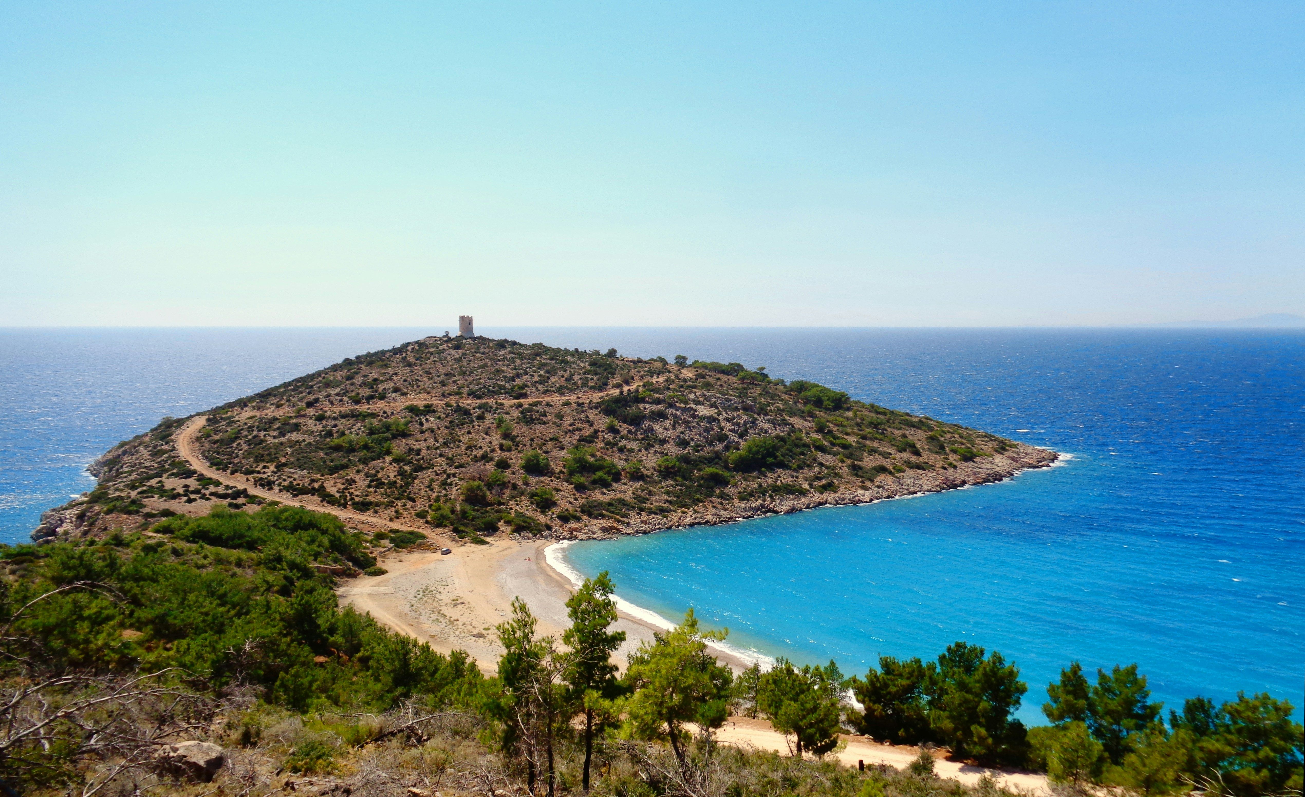 sandy bay surrounded by green hills
