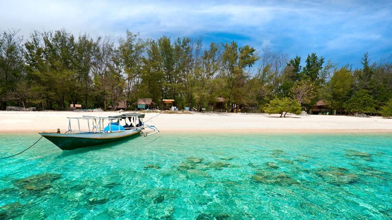 boat docked on a white sand beach in Gili Meno