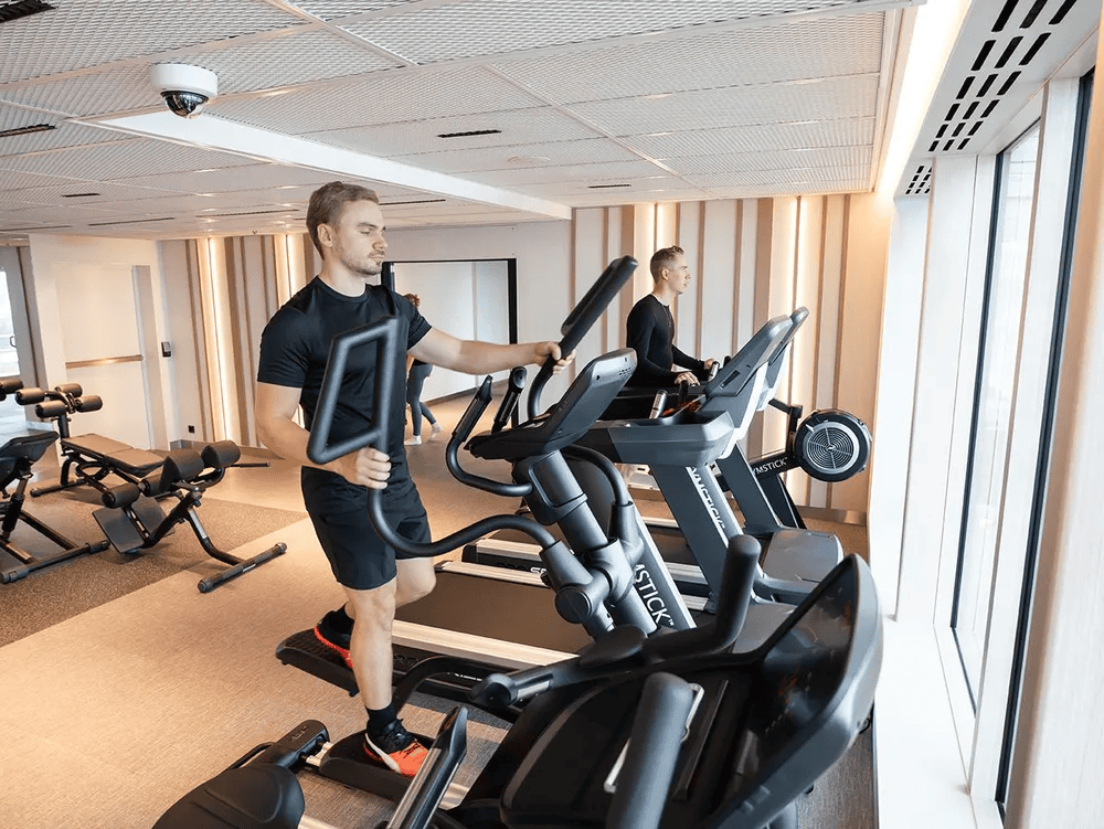 Personas entrenando en el gimnasio del Finnsirius con vista al mar