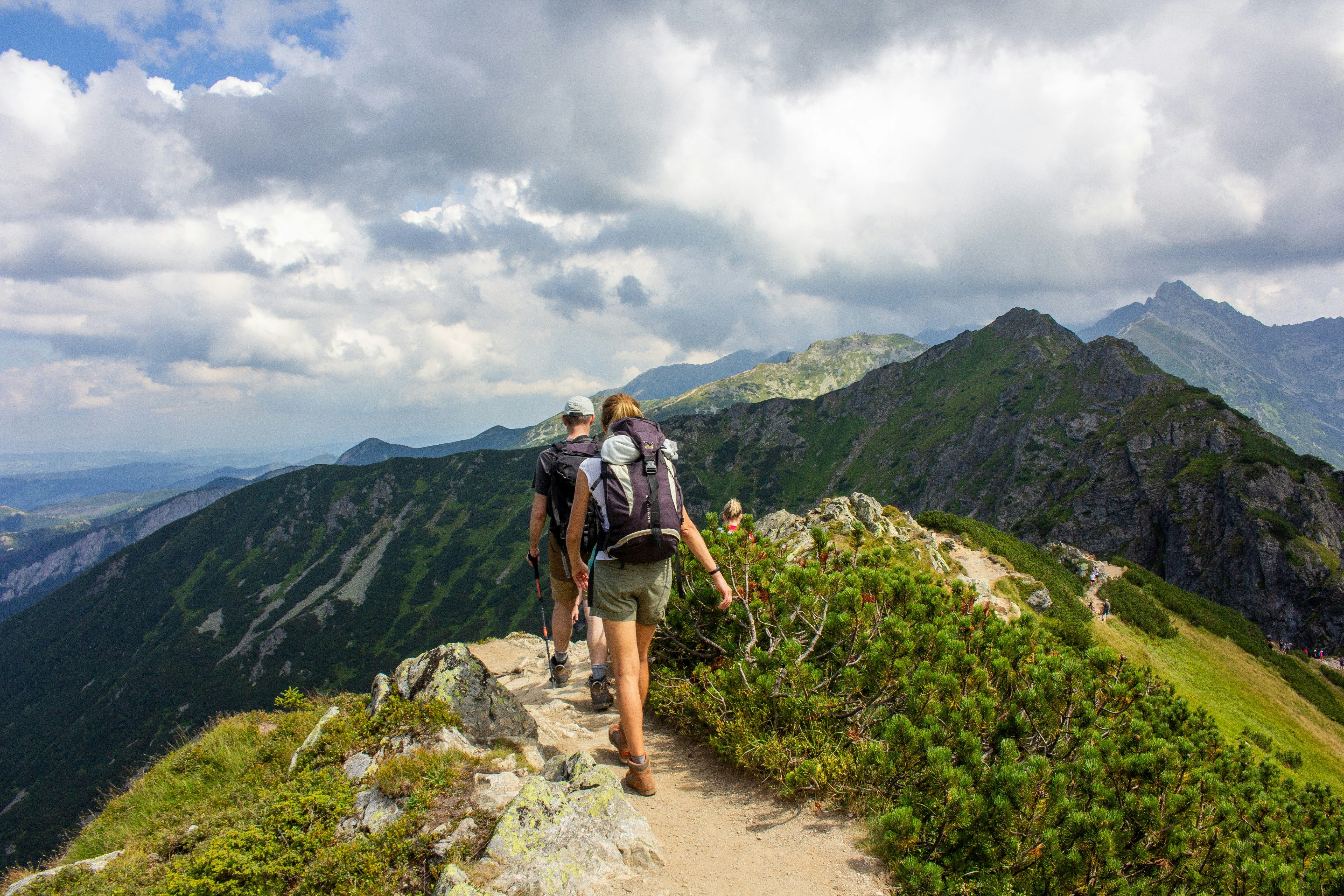 two people walking on top of a mountain